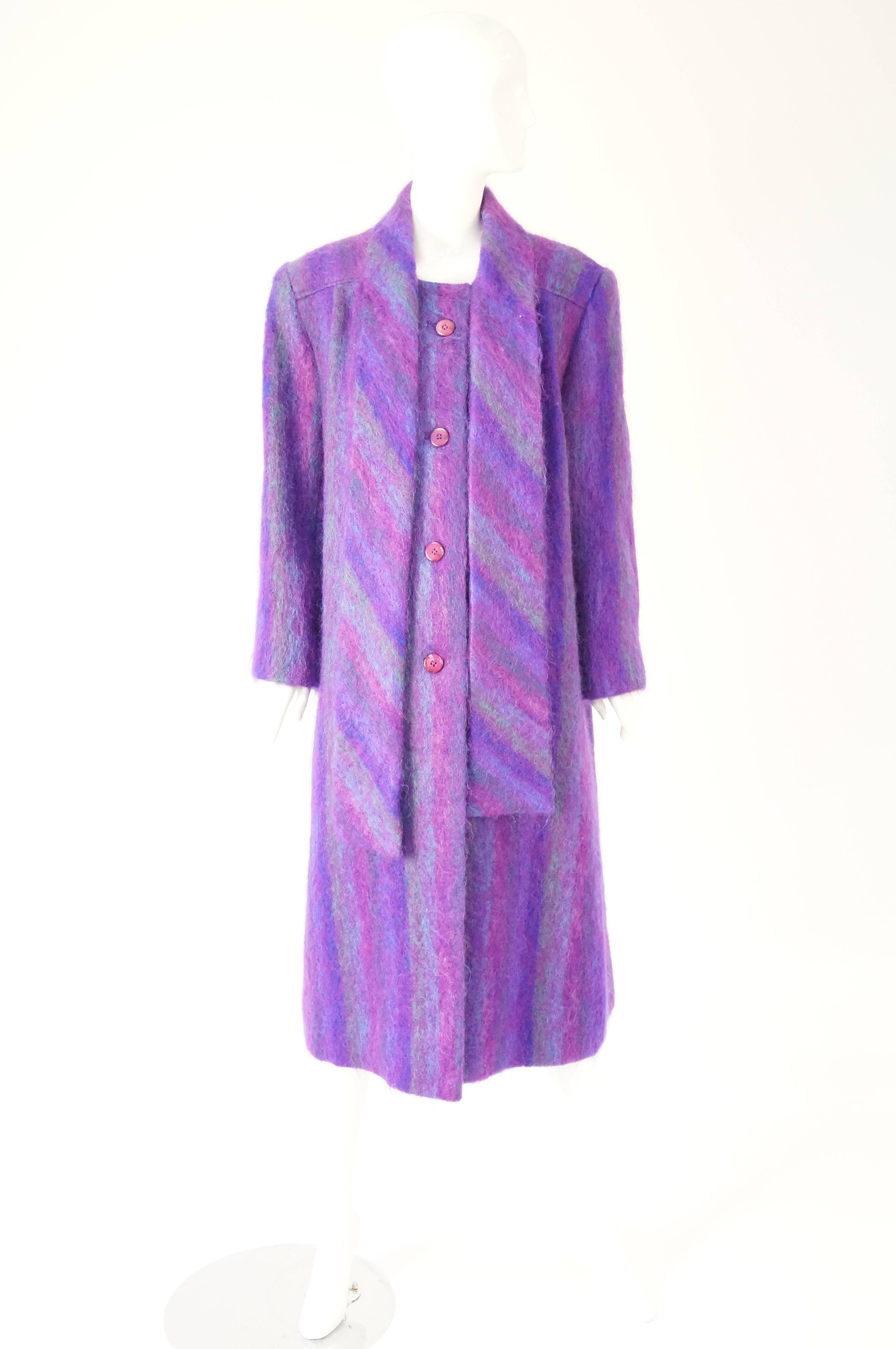 
Absolutely striking coat of plush mohair with a primarily purple background with grey, blue, and pink stripes by the Riel Coat Co.  

It has buttons going down the front, and has a dramatic length of fabric at the collar, that can be tied in a bow