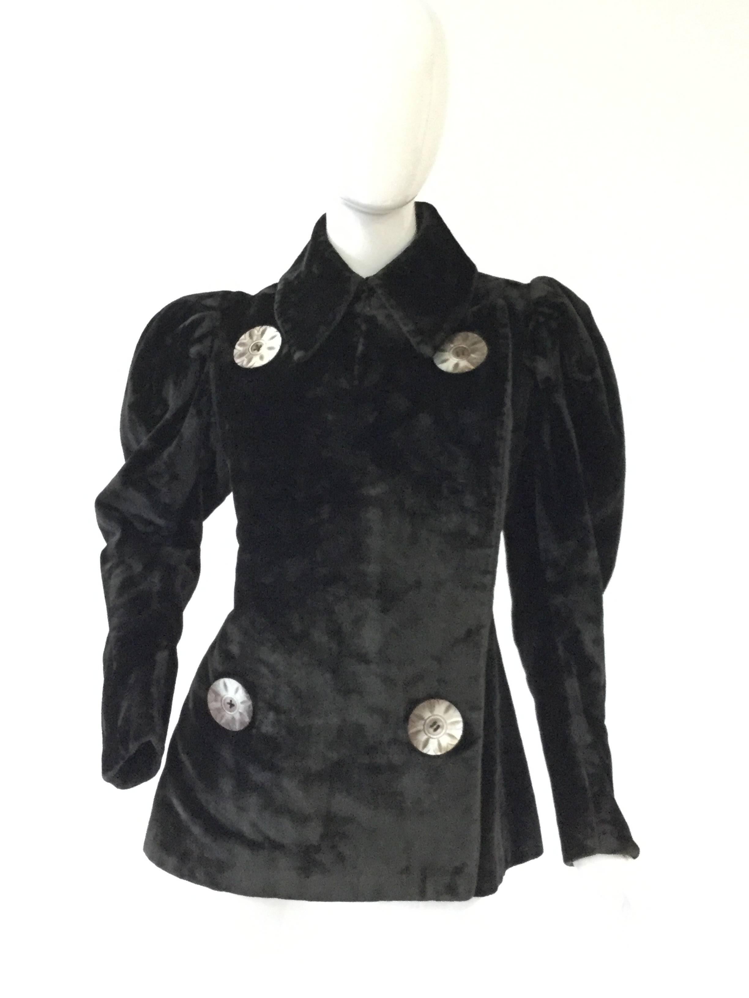 
Stunning. This impeccably preserved velvet coat has long mutton sleeves, tall lapel collar, a long overlapping breast panel, and a pleated peplum back originally designed to fit over a bustle! The massive mother of pearl buttons with a radial