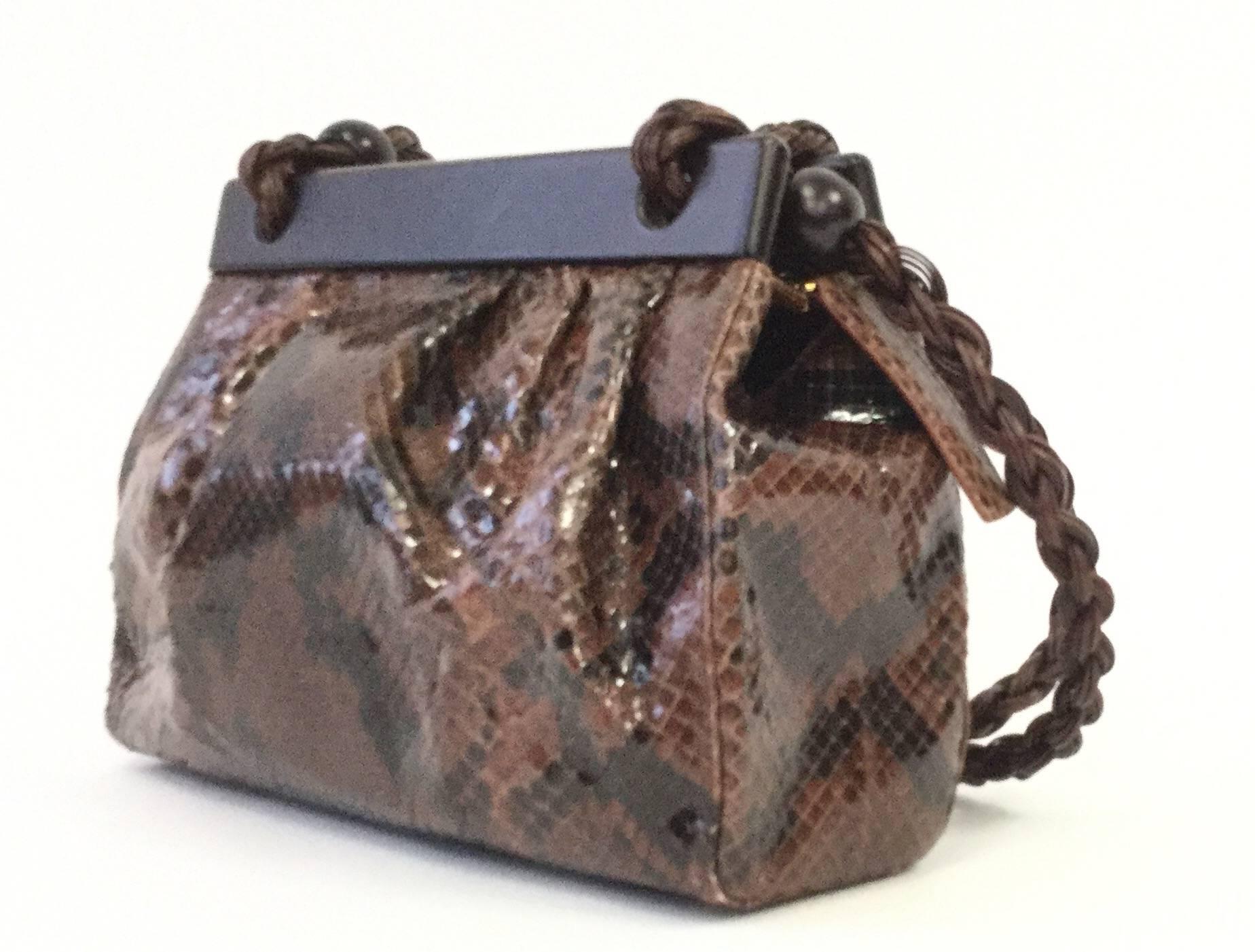 Gorgeous vintage handbag by Suarez New York! This plush bag is composed of a cinnamon brown python leather body with polished wooden clasp-like top and braided leather straps with wooden ball accents. The purse has our gold-tone metal feet and a