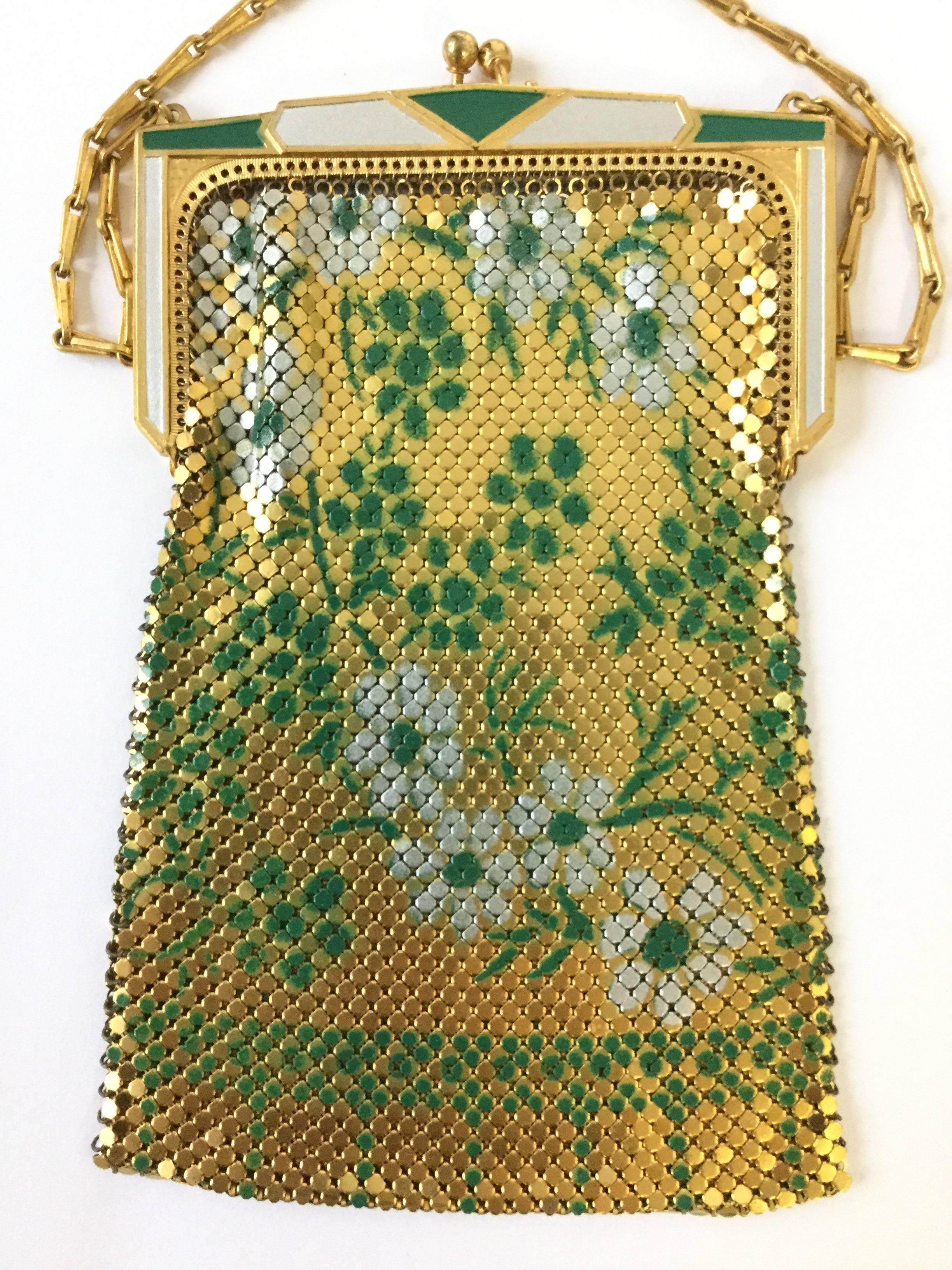 
Glitzy and glamorous 1920s Whiting and Davis evening purse! This gorgeous enamel mesh purse features an art deco clasp painted in alternating white and green. The mesh body of the purse has a floral design consisting of sprigs of white and green