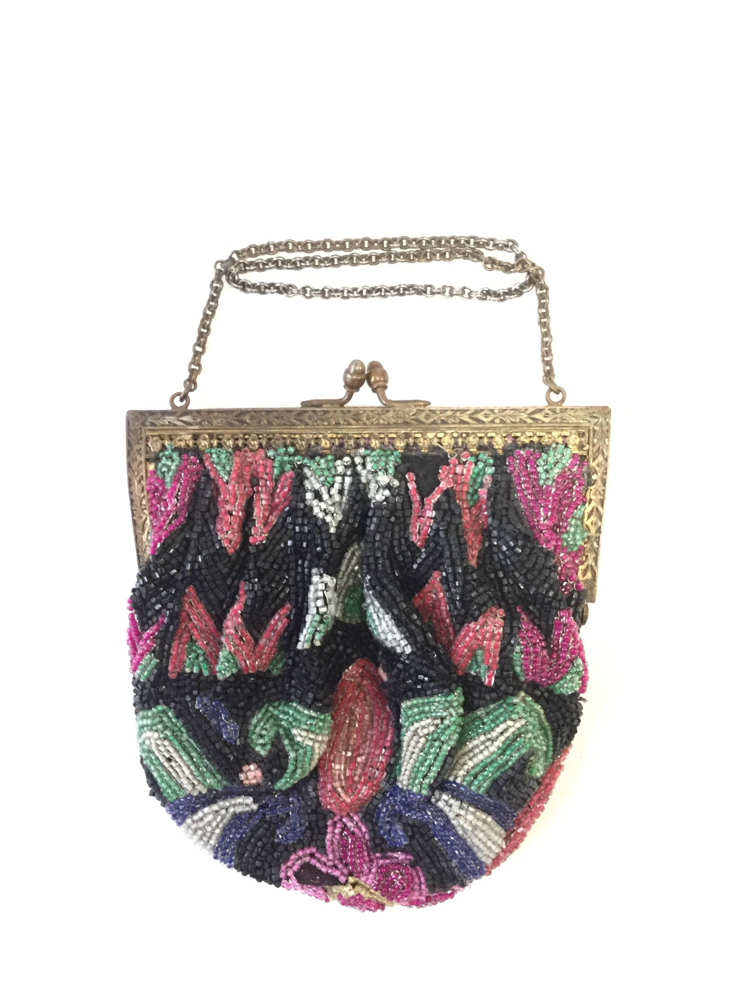 
Gorgeous fully beaded antique purse. This purse features a gorgeous radial floral design stemming from the bottom center of the piece. The design is composed of a bright and colorful pink flower with yellow accents, surrounded by leaves and other