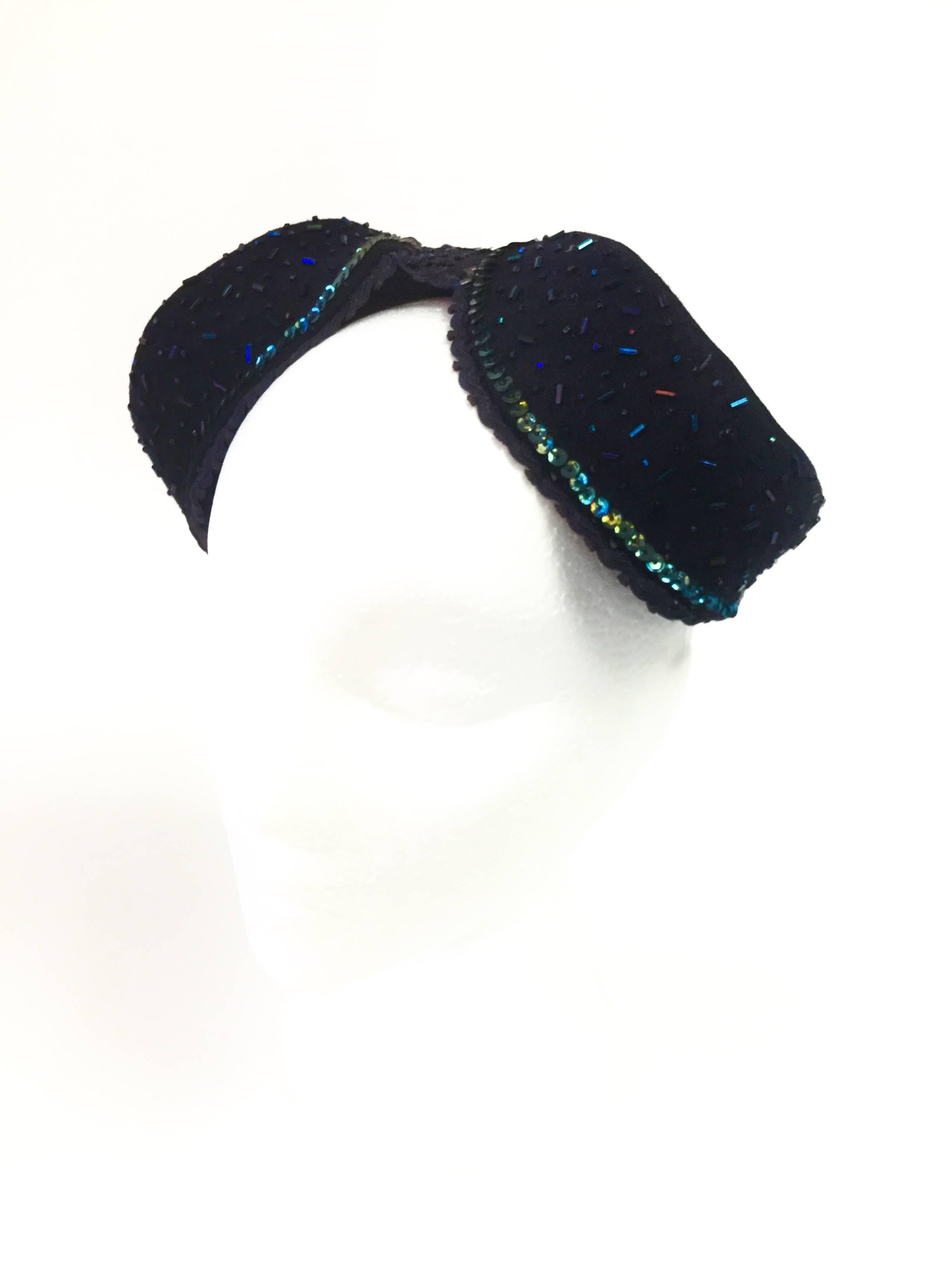 
This gorgeous and rather unique vintage felt hat by Pierre Renand  exclusively for Sakowitz Brothers features two crowns set at both sides of the hat that meet together in the fully beaded center. The sides of the crown are fully beaded in a