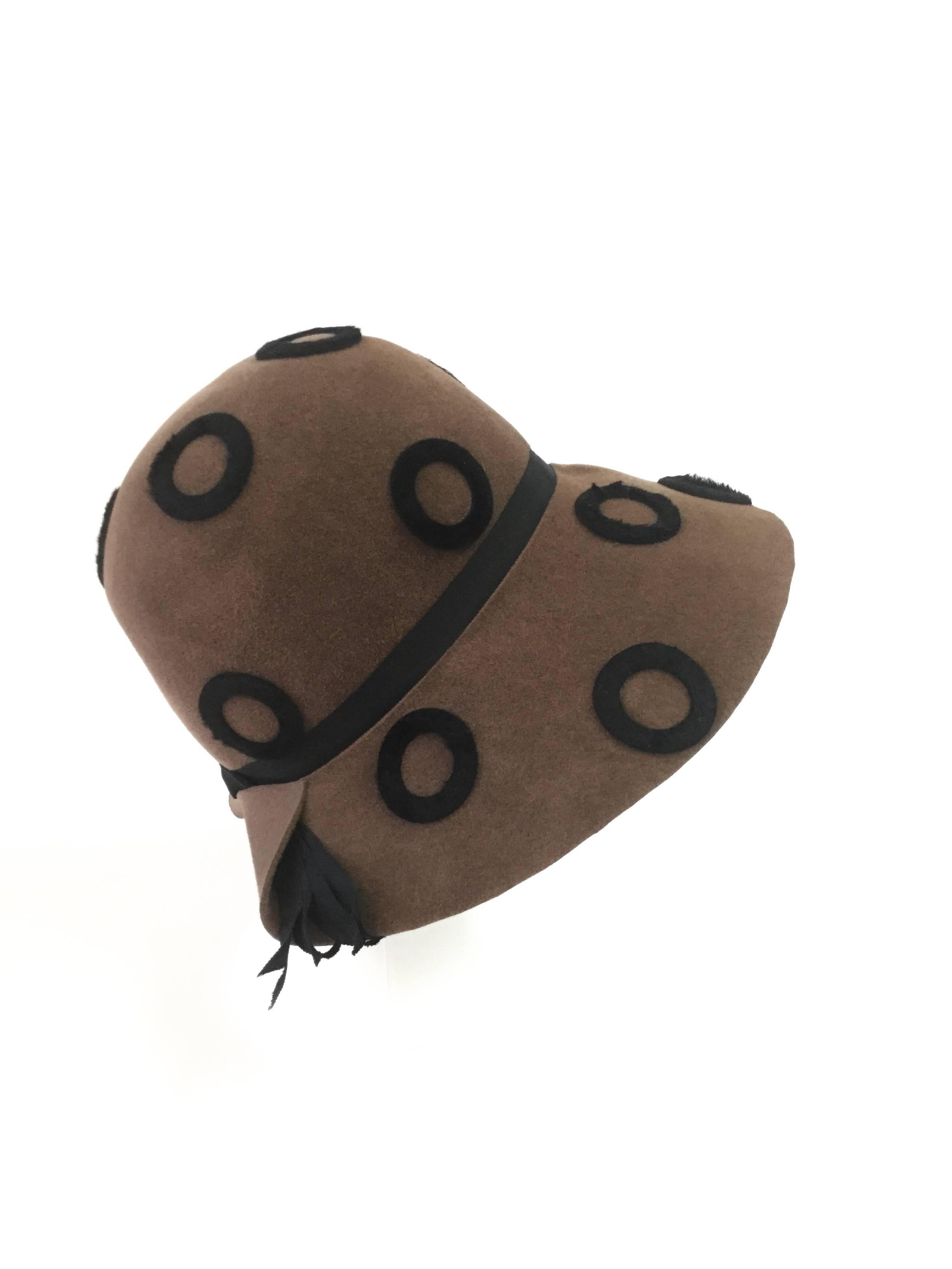 
This fantastic bohemian felt hat by Miss Carnegie by Hattie Carnegie has a rounded crown and a distinctive folded notch at the back of the wide brim. The hat features a polkadot pattern throughout, a thin grosgrain ribbon at the base of the crown,