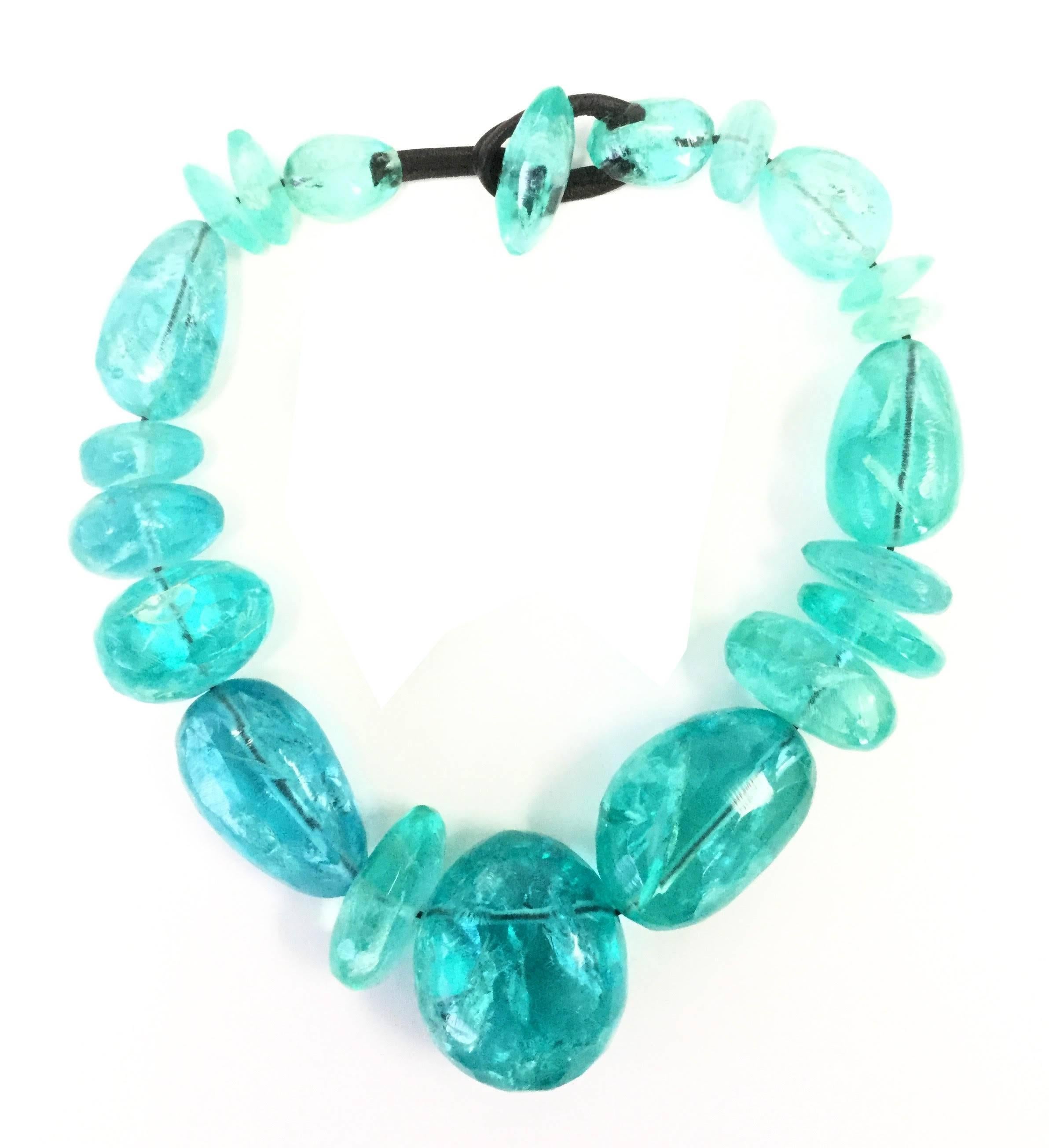 
This gorgeous demi parure created by Gerda Lynnggaard for Nikoli Monies is composed of a set of earrings and a necklace, both made of the same incredible ice blue beads held together on a leather cord. The beads feature expertly molded rifts and