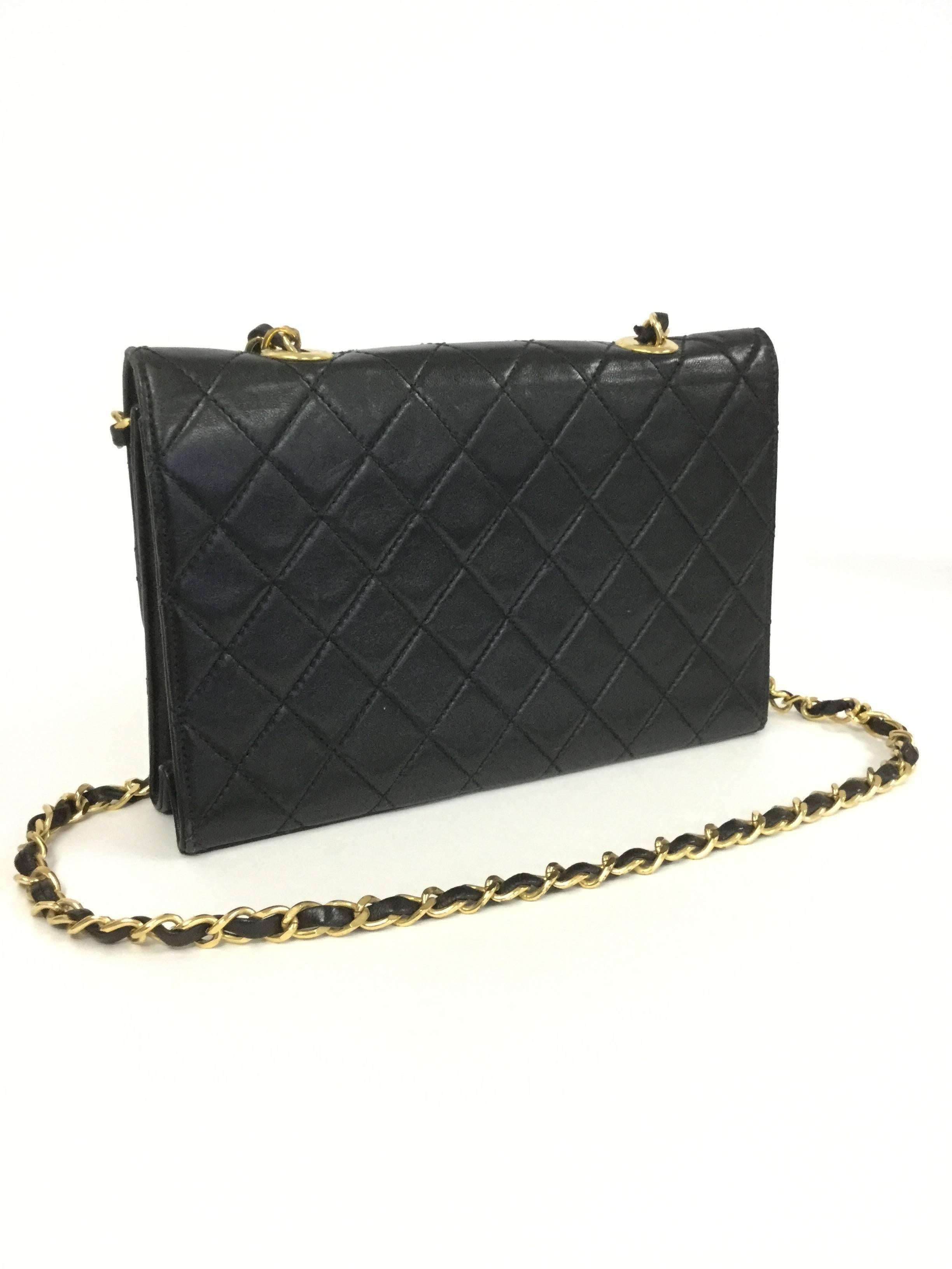 
This 1980's Mila Schon purse has a unframed box body made of supple black quilted leather. The purse has a fold over flap featuring the Mila Schon logo and is adorned with a chain. A magnetic button clasp is situated on the reverse of the flap. The