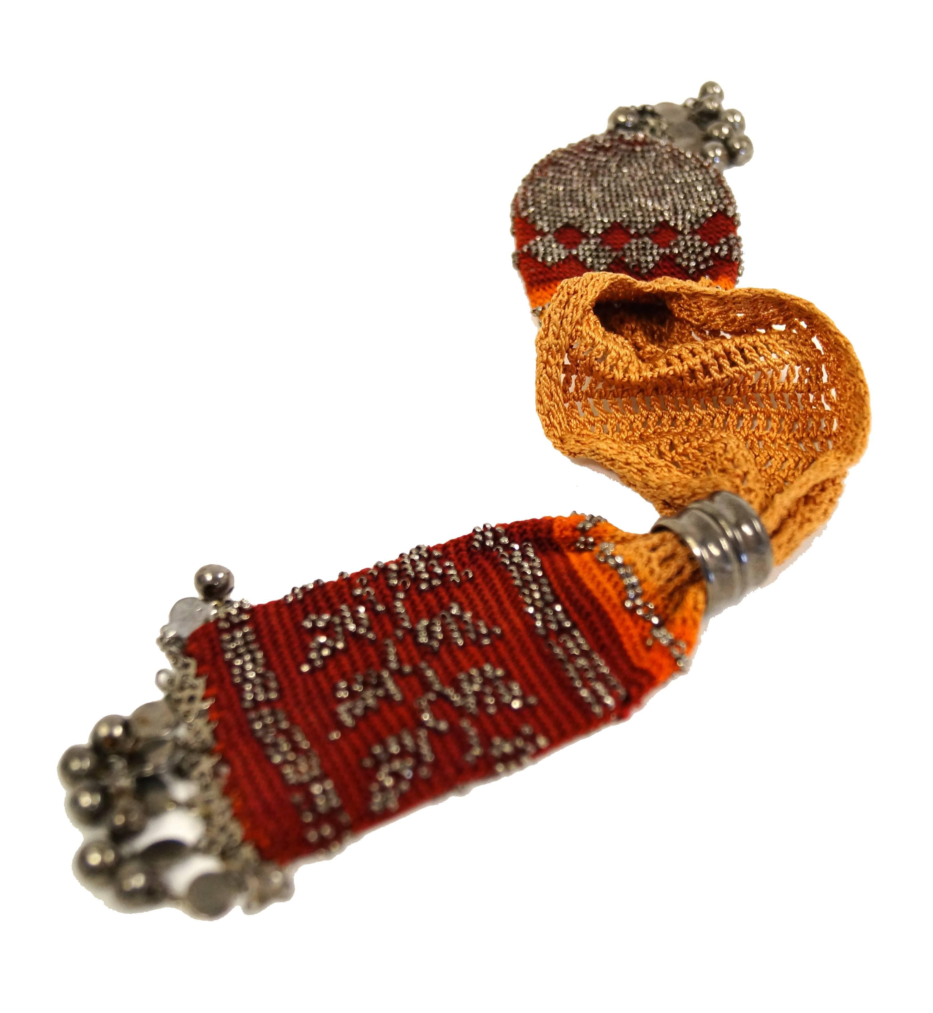 Fantastic orange and burgundy hand made crochet miser's purse with rough hewn multifaceted beads. This fine example of mid 19th century fashion is meticulously sewn in a vine and argyle diamond pattern.  The bag has metal spherical beads dangling