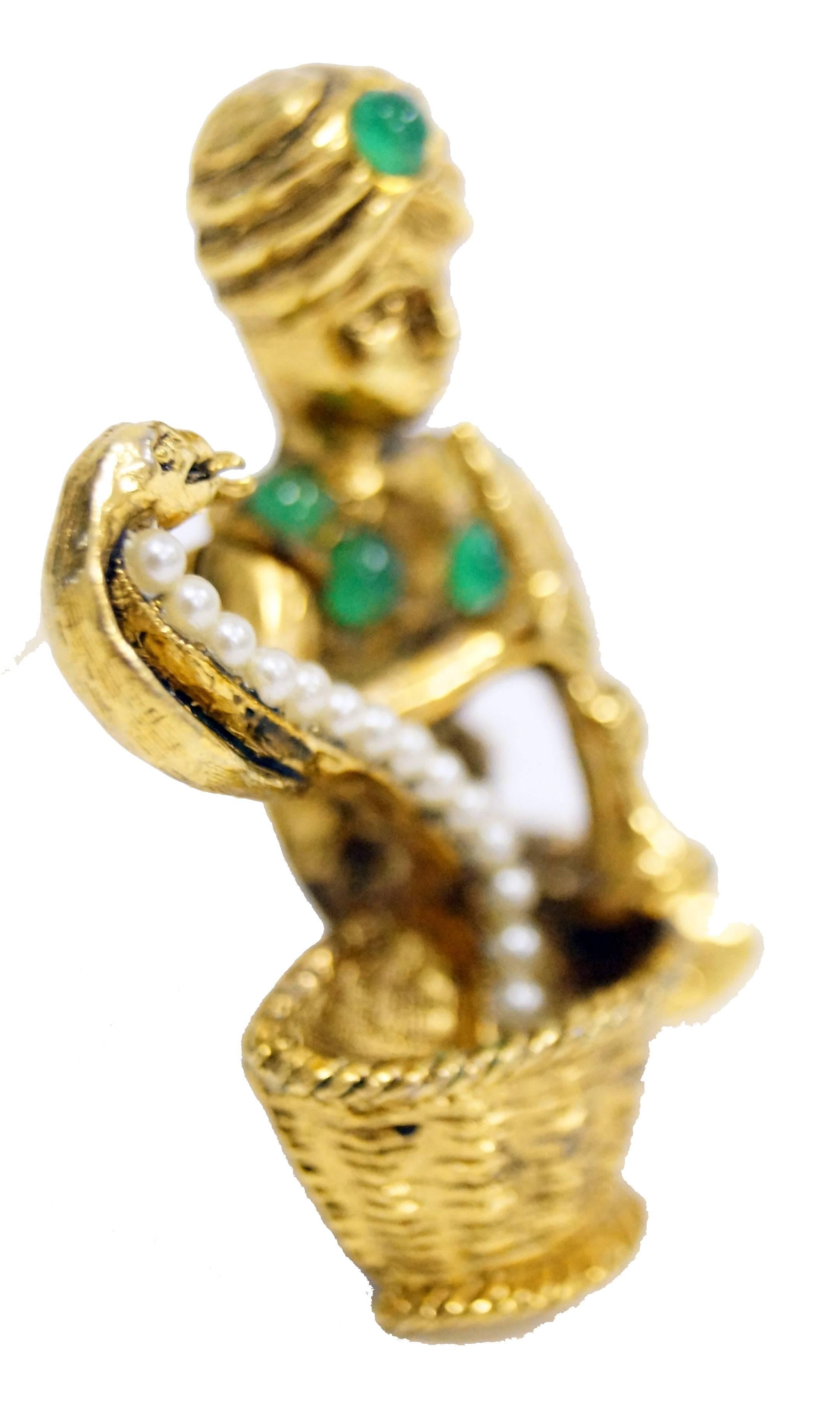 1960s Hattie Carnegie Snake Charmer Brooch

We are absolutely charmed by this mid century figural brooch by Hattie Carnegie. The gold tone brooch depicts a cross-legged snake charmer playing his pungi flute and coaxing a cobra out of a woven basket.