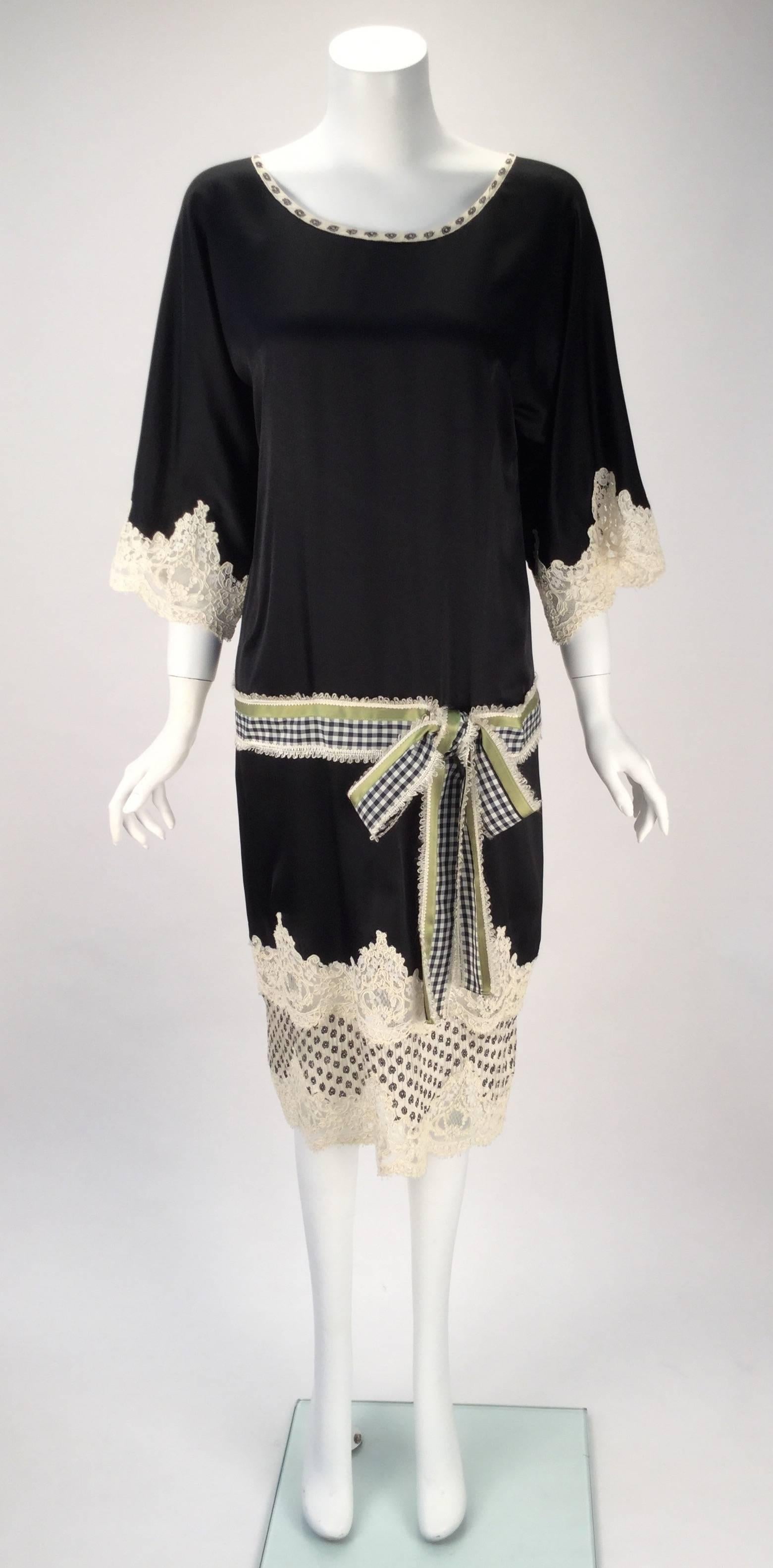 Beautiful, sweet, and fun Geoffrey Beene black dress. The dress is made of silk with alencon lace. Lovely kimono sleeves fall from the shift shaped bodice. The alecon lace trim dangles from both the sleeves and hem. The belt is made up of Navy blue