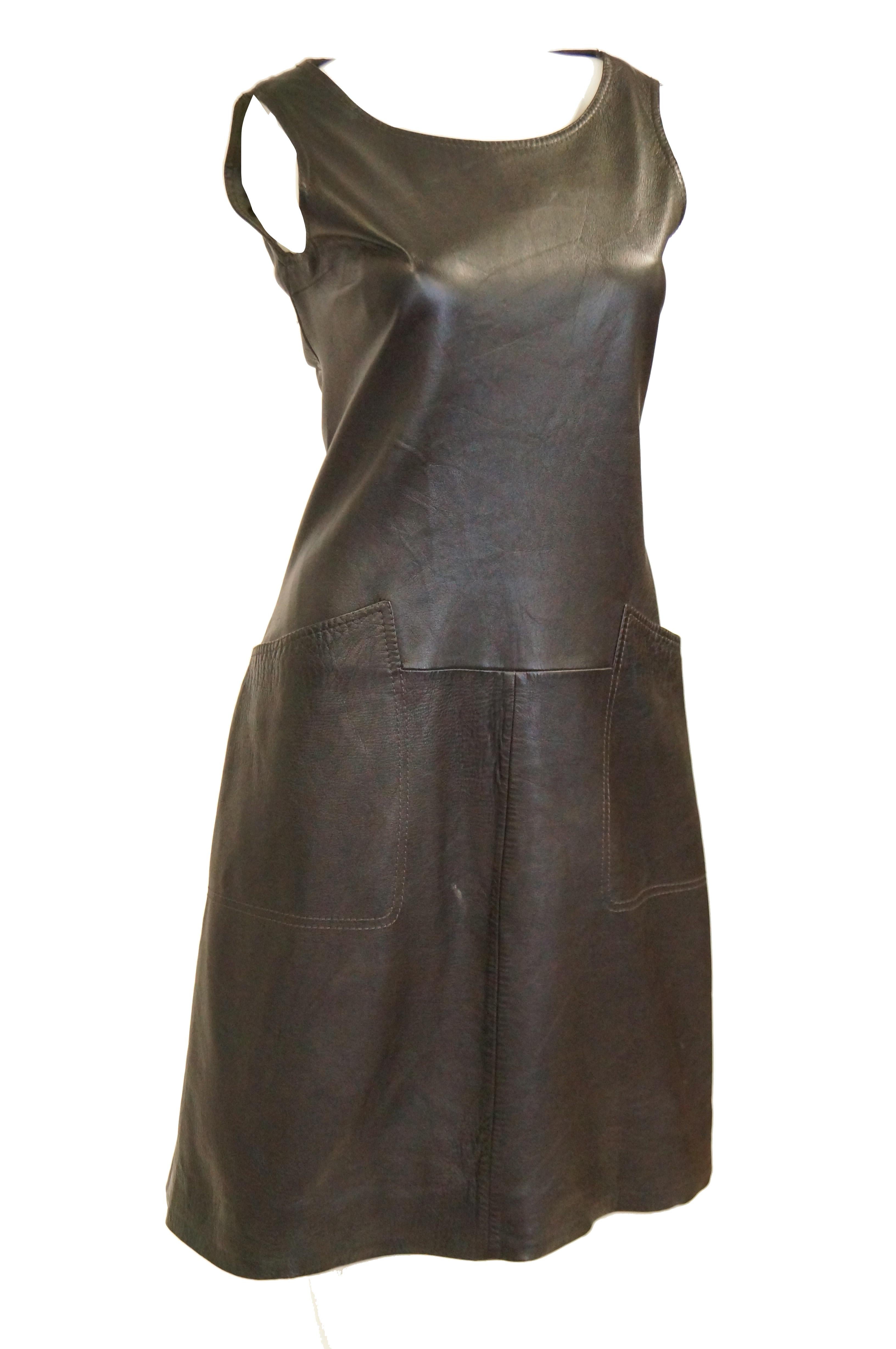 Buttery soft lambskin dress in espresso brown. The shift dress is knee length, sleeveless, and has a wide, round neckline. The dress features square pockets, with seams that blend into the waist structure of the dress. Wear with a white turtleneck