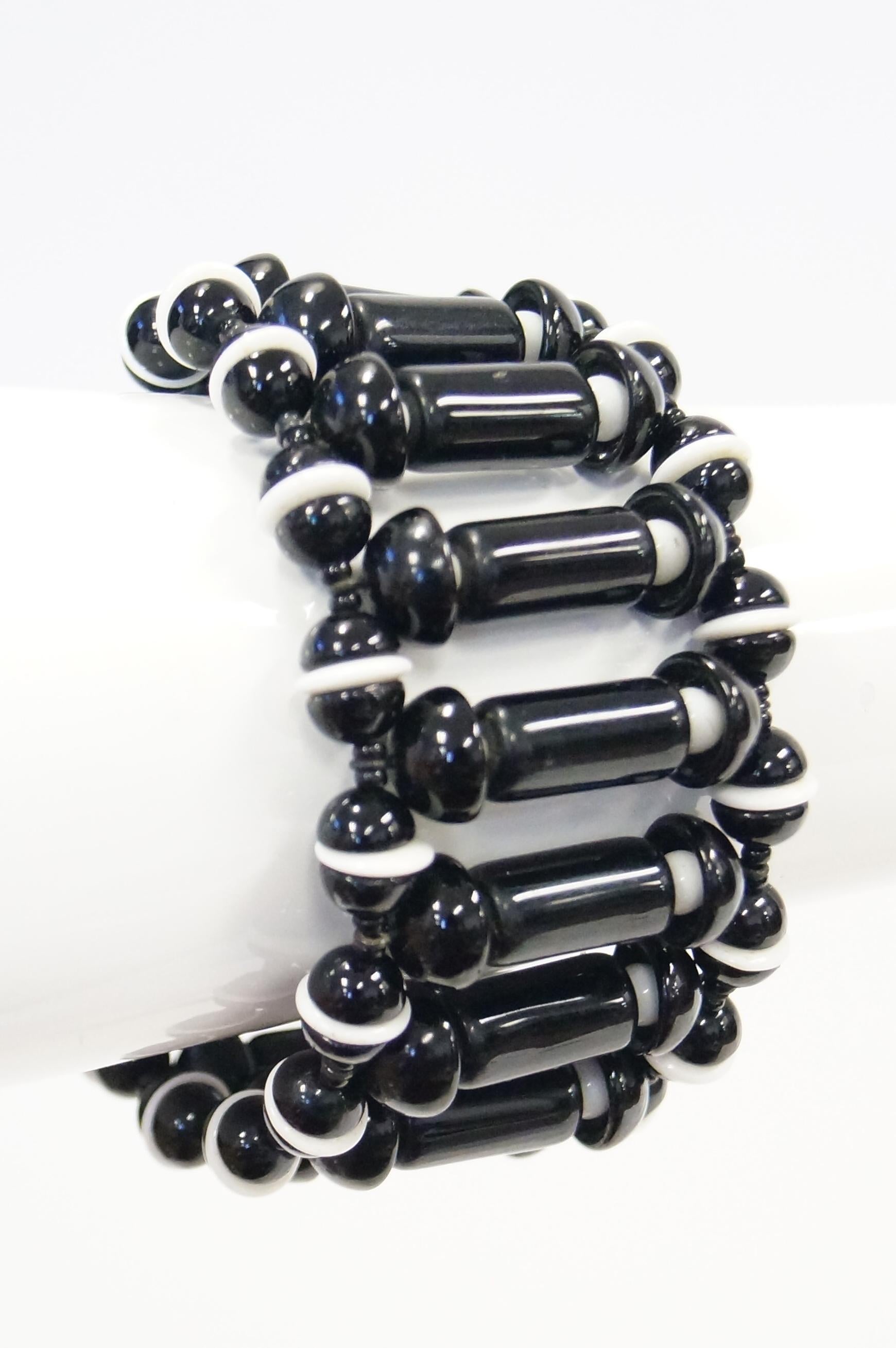 Mod Black and white glass cuff bracelet with safety chain. Tubular and mushroom cap beads come together creating a stylish piece of arm art. This large statement cuff  is all you need to compliment your look day or evening. The scale of the cuff is