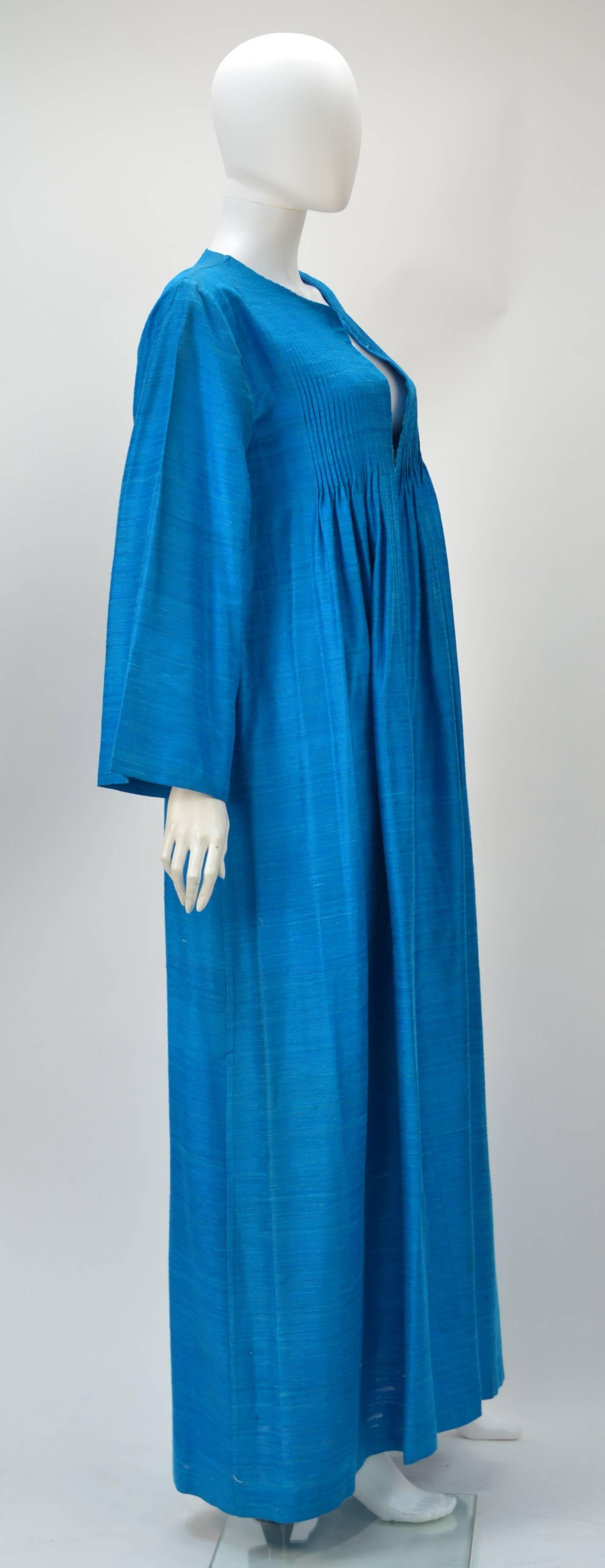 Elegant...Ethnic...Comfort!

Beautiful 1970's azure blue long sleeve silk caftan made by collectible designer Marti of Mexico. The caftan features multiple clean lines of pin-tucking at the bust and a deep V- neckline. This features no closures, as