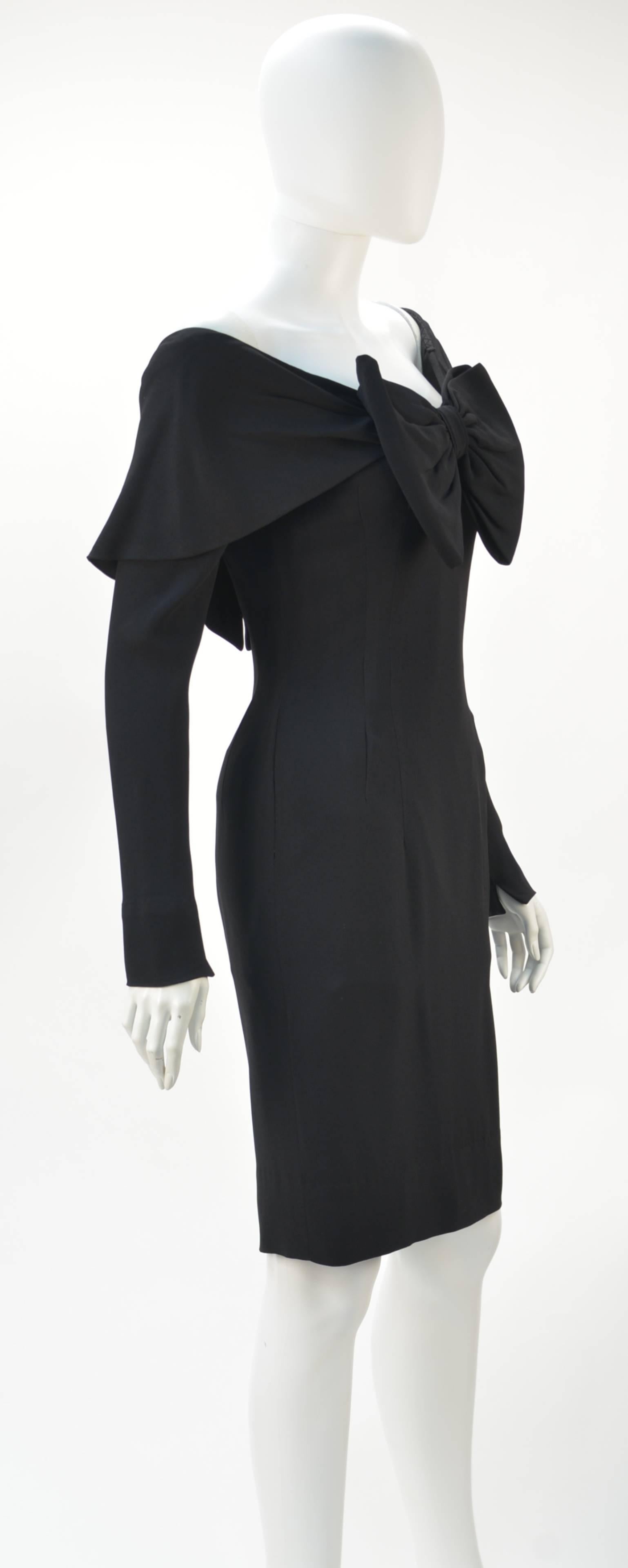 Bombshell and elegant 1950's Mr. Blackwell black crepe wiggle style dress with shawl collar and long sleeves.  A bow at center front neck adds a subtle feminine touch to the dress. Back zipper with a hook-and-eye closure.  Perfect for almost any