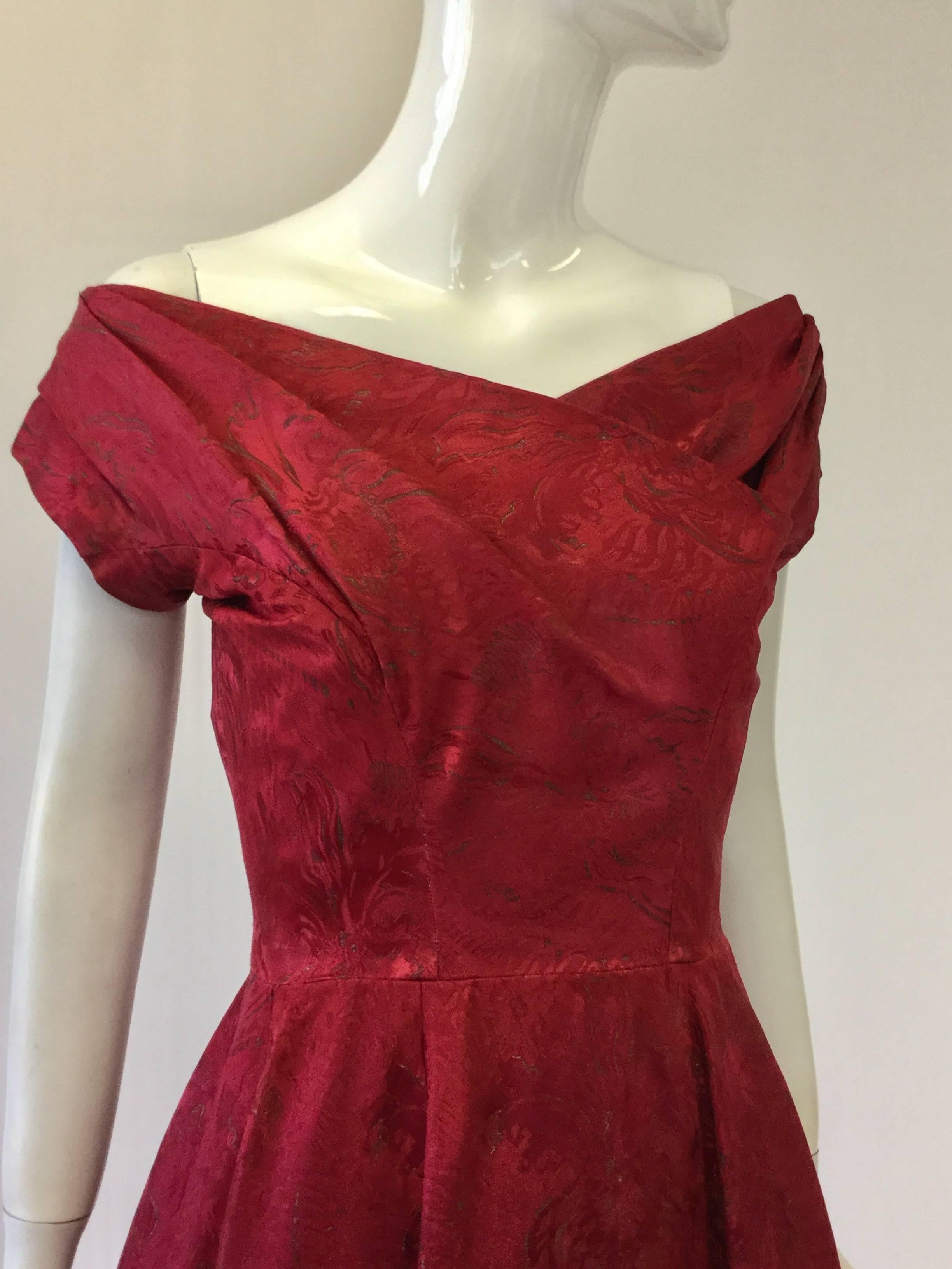 This exquisite burgundy silk satin and gold brocade ball gown is labeled "Christian Dior Made in England by C.D.Models." This orchid pattern, off the shoulder dress, has a ruched criss-cross pleat bust line. The gown has a boned red tulle