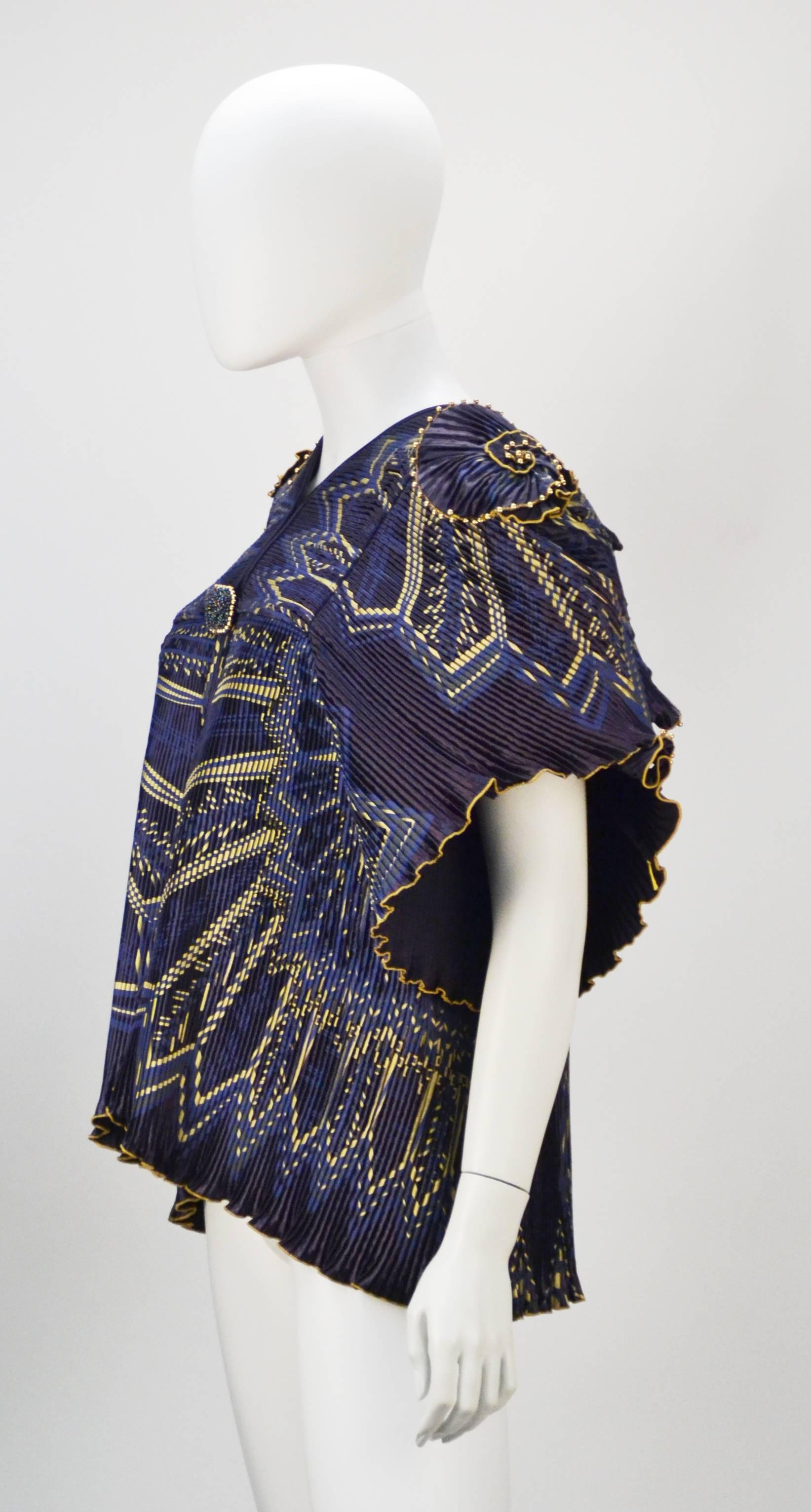1970's Zandra Rhodes navy blue satin faced with gold dry print geometric print jacket. 100% rayon. The gorgeous statement piece features micro accordion pleating and a exquisite blue and gold pattern using one of her signature silk screening