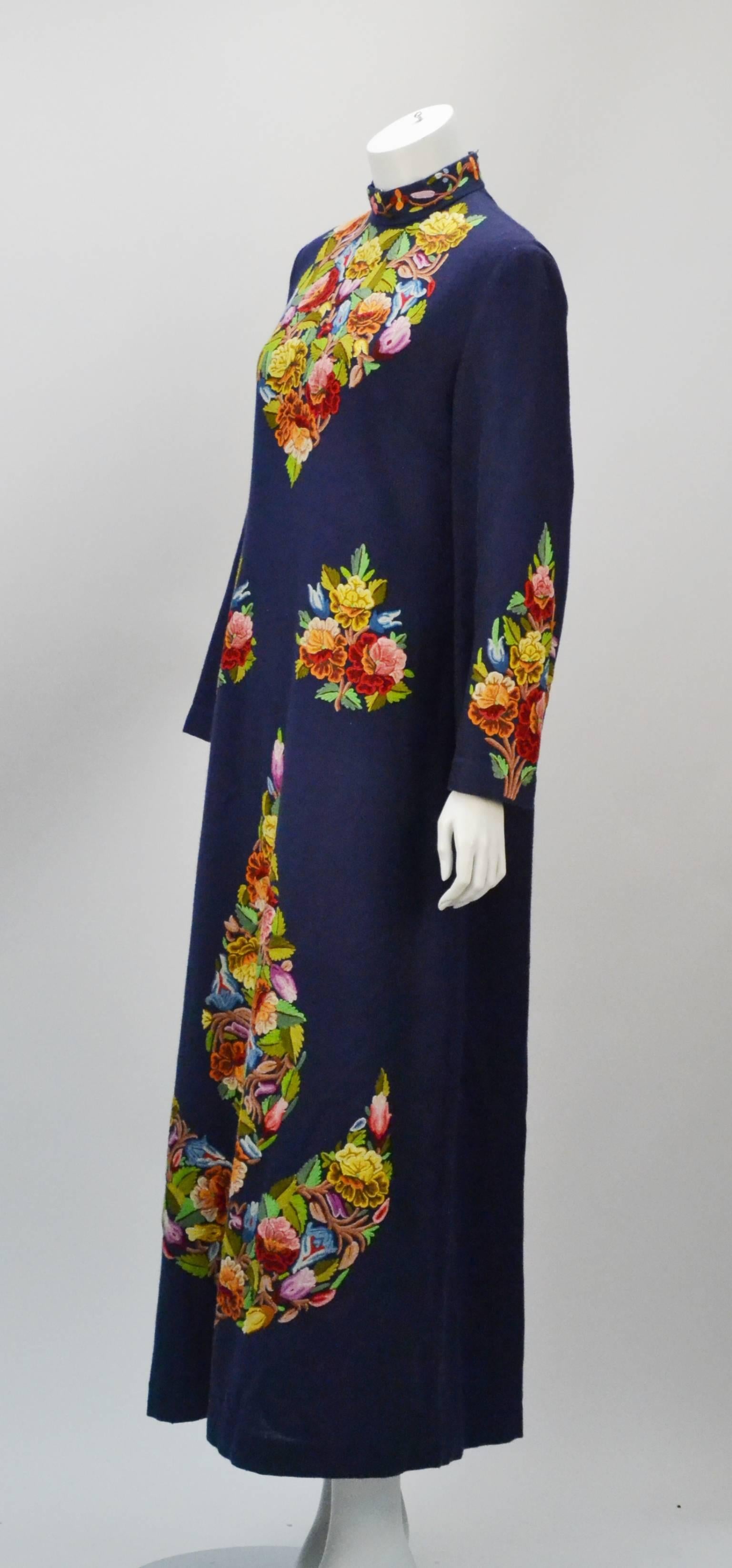Wonderful long navy blue kaftan/shift dress with long sleeves. It features a standing collar and impeccable multi color embroidered floral scene. Dress is made of wool and lined with what appears to be a natural fibered silk and cotton blend.  Metal