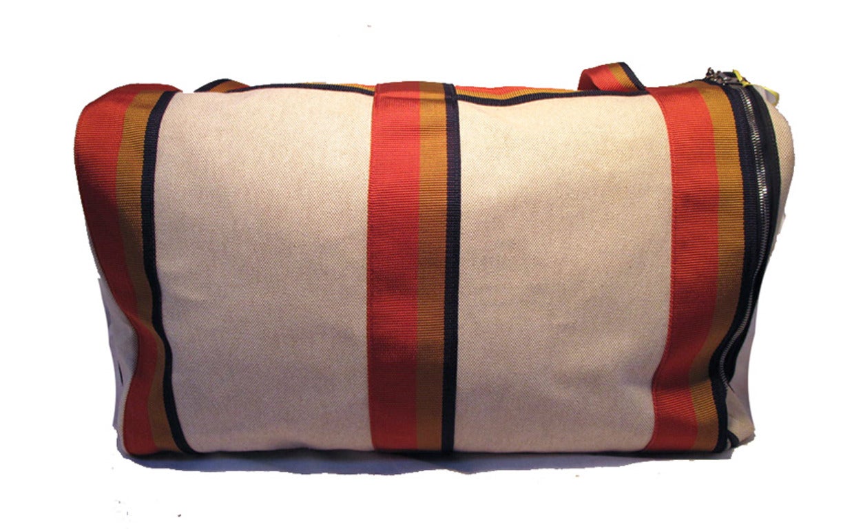 AMAZING HERMES canvas striped duffel travel tote in excellent condition.  Beige canvas toile exterior trimmed with red, blue, and gold nylon straps.  Top double zipper closure opens to a tan canvas lined interior that holds ample room for all your