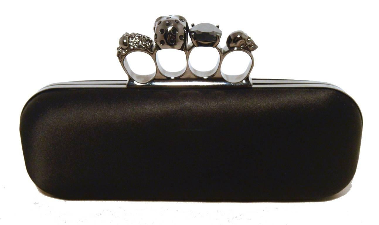 Rare Alexander Mcqueen black satin knuckle ring clutch in excellent condition.  Black satin exterior trimmed with gunmetal hardware and unique knuckle ring top.  4 finger holes for carrying with skulls, a large onyx stone and floral design on each