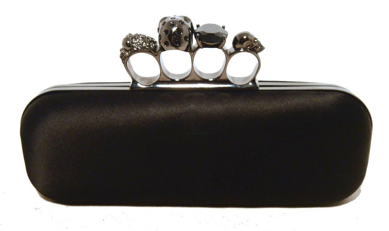 Seltene Alexander Mcqueen Clutch aus schwarzem Satin mit Schlagring in ausgezeichnetem Zustand.  Schwarzes satiniertes Äußeres:: verziert mit Rotgussbeschlägen und einzigartigem Knöchelring oben.  4 Fingerlöcher zum Tragen mit Totenköpfen:: einem