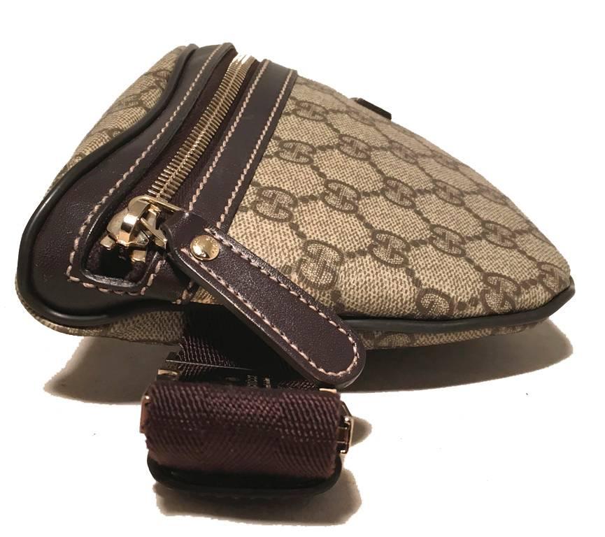 Classic Gucci belt bag in excellent condition.  Signature monogram coated canvas with brown leather trim. Woven canvas adjustable strap with gold buckle closure.  Front zipper closure opens to a brown canvas lined interior that holds 1 side slit