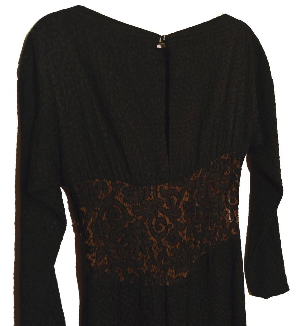 Black puckered pongee silk gown with an embroidery underbust lace inset that is lined with a flesh colored silk.  There is an inverted half bow that cascades down the front of the dress.  The dress has set in long dolman sleeves.  Button closer at