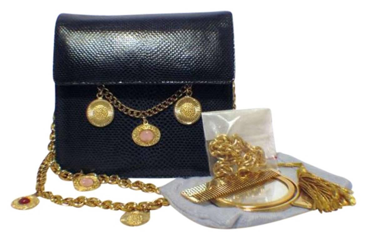 This beautiful Judith Leiber piece is in excellent condition. The exterior features stunning navy blue lizard leather trimmed with gold coin and chain detailing along the front side and shoulder strap. The magnetic snap single flap closure opens to