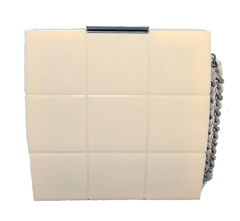 Timeless Chanel box clutch wristlet in excellent condition.  Cream acrylic resin in quilted box shape trimmed with matte silver hardware and woven chain and leather wrist strap.  Top button closure opens to a beige leather lined interior that holds