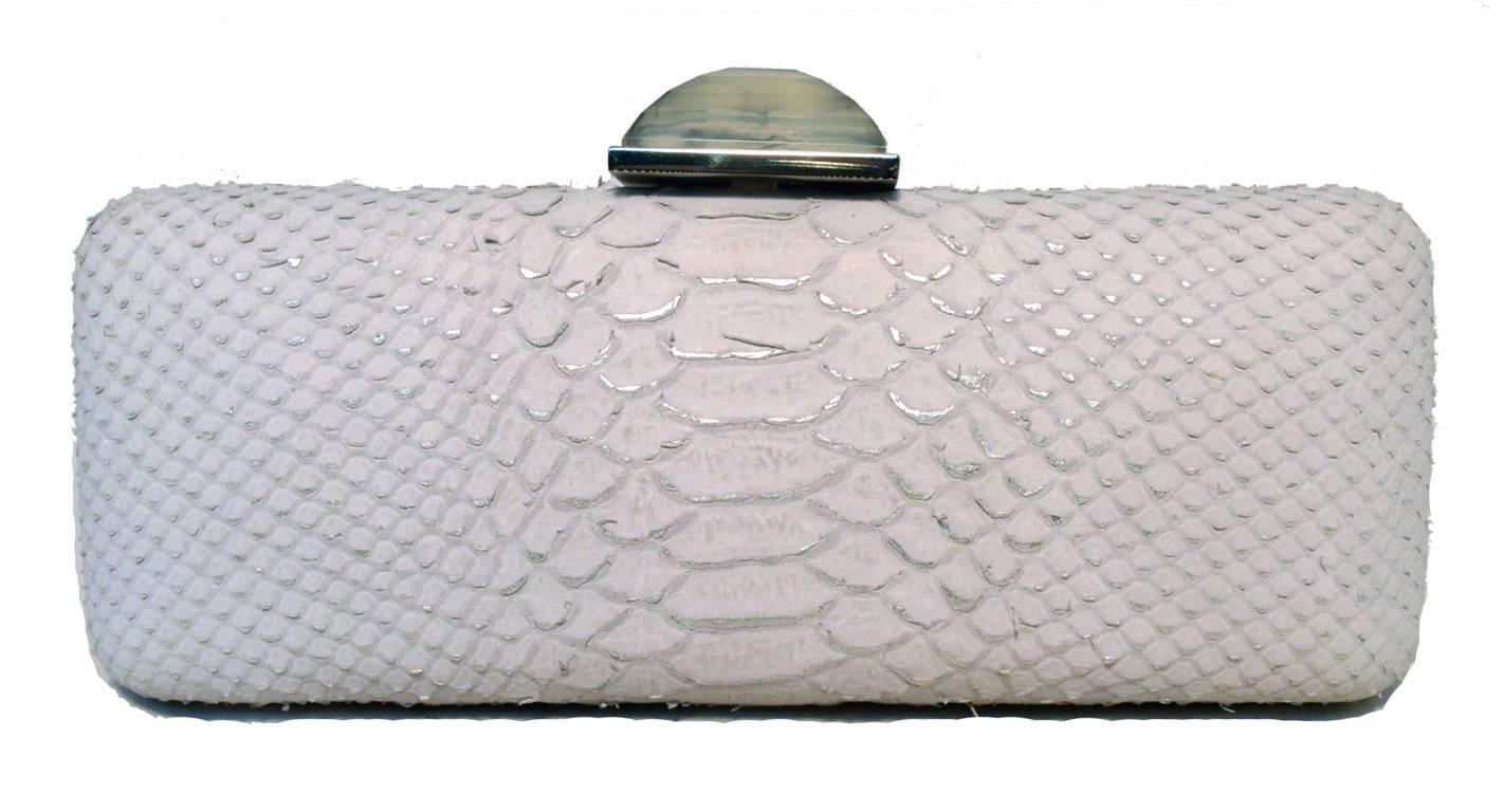 Judith Leiber Overture Clutch in excellent condition.  White snakeskin exterior with silver hardware and top pyramid quartz stone.  Lifting top closure opens to a silver leather lined interior that holds an attached silver chain link shoulder strap