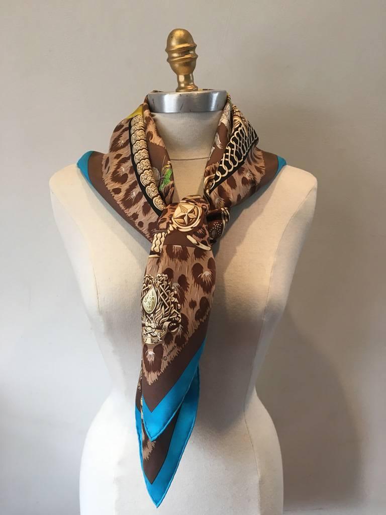 Beautiful vintage Hermes silk Casques et Plumets silk scarf in excellent condition.  Original silk screen design c1989 by Julia Abadie features a turquoise blue border with brown and animal print background.  Various knight in shining armor head