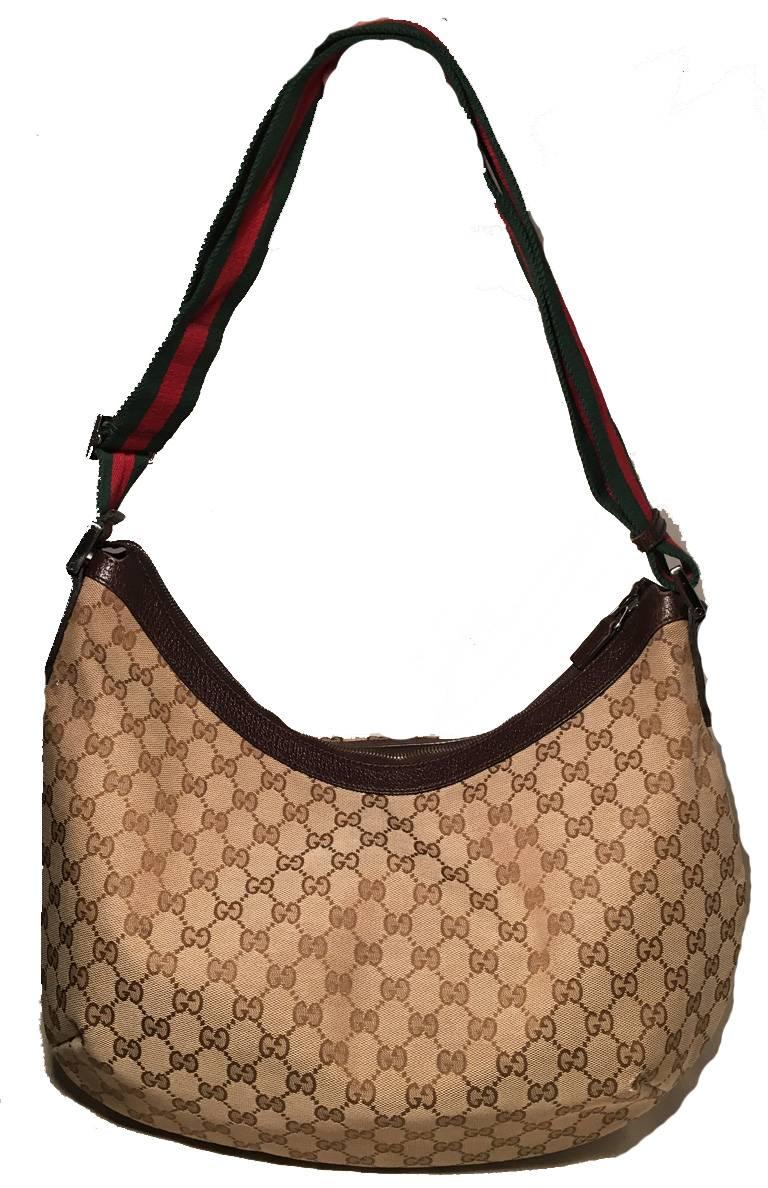CLASSIC Gucci monogram hobo shoulder bag in excellent condition.  Monogram canvas exterior trimmed with dark brown leather and a woven green and red striped adjustable shoulder strap. Top zipper closure opens to a brown nylon interior that holds 1