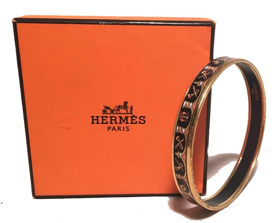 GORGEOUS Hermes thin enamel bracelet in excellent condition.  Musical instrument print over a black background trimmed with gold hardware and black backing.  Stamped Hermes, Made in Austria 