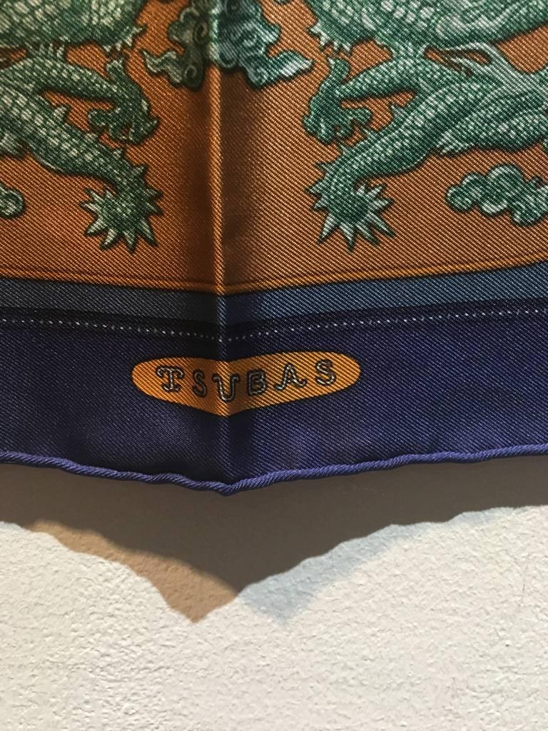 BEAUTIFUL Hermes Tsubas silk pocket square scarf in excellent condition.  Original silk screen design c1970s by Christiane Vauzelles features a beautiful display of ropes and tassels in golds over a navy blue background.  100% silk, hand rolled hem.