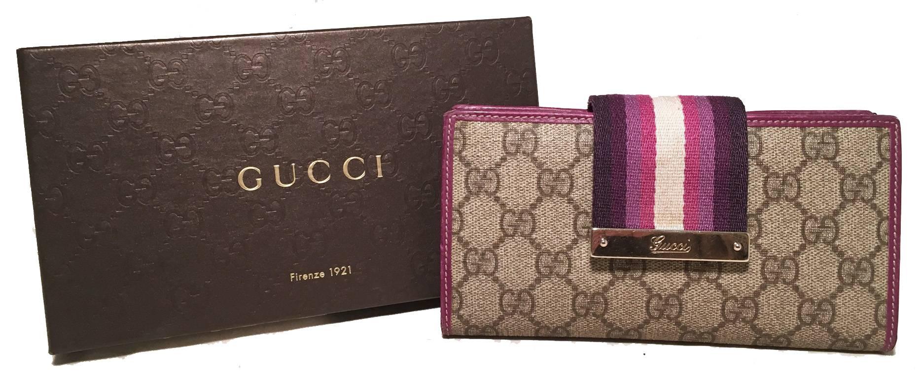 GORGEOUS GUCCI monogram and canvas wallet in very good condition.  Signature brown gucci monogram canvas exterior trimmed with fuchsia leather and a striped woven canvas snap strap closure.  Fuchsia leather lined interior with multiple card slot