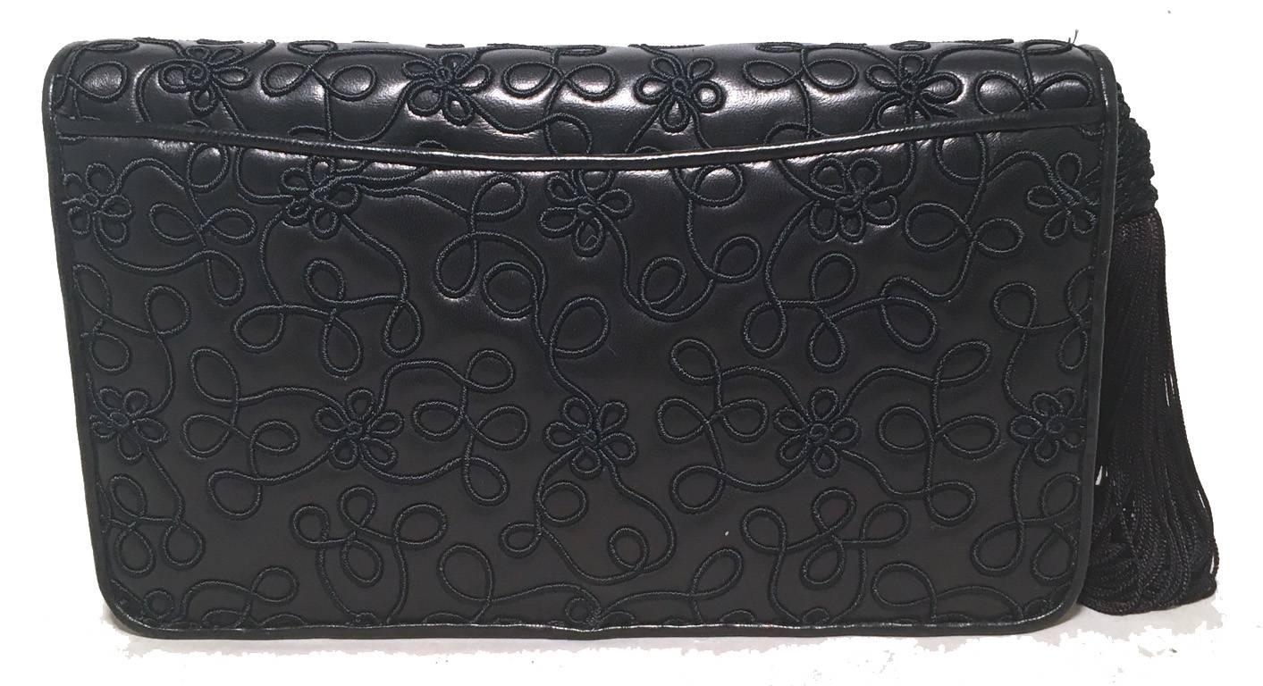 Gorgeous Judith Leiber embroidered leather clutch in excellent condition.  Navy blue leather exterior trimmed with a embroidered details and tassel.  Snap flap closure opens to a navy blue nylon interior that holds 3 separate storage compartments. 