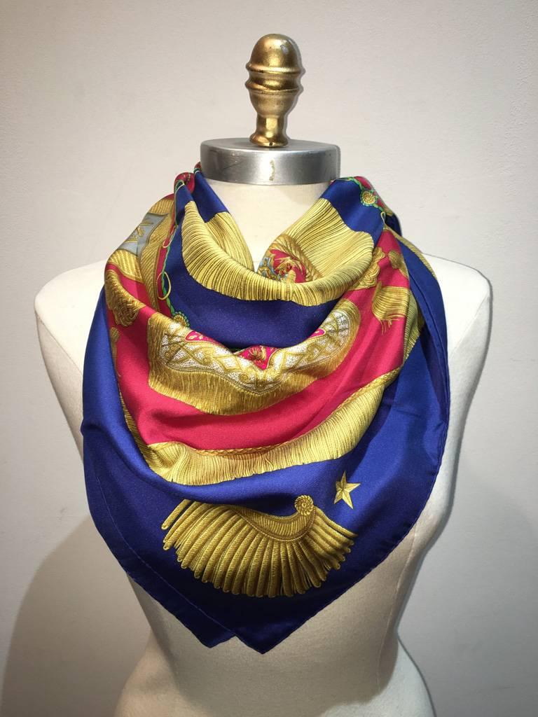 GORGEOUS Hermes vintage poste et cavalerie silk scarf in excellent condition.  Original silk screen design c1980s by Joachim Metz features an array of golden post cavalry dressings over a red and blue background.  100% silk, hand rolled hem, made in