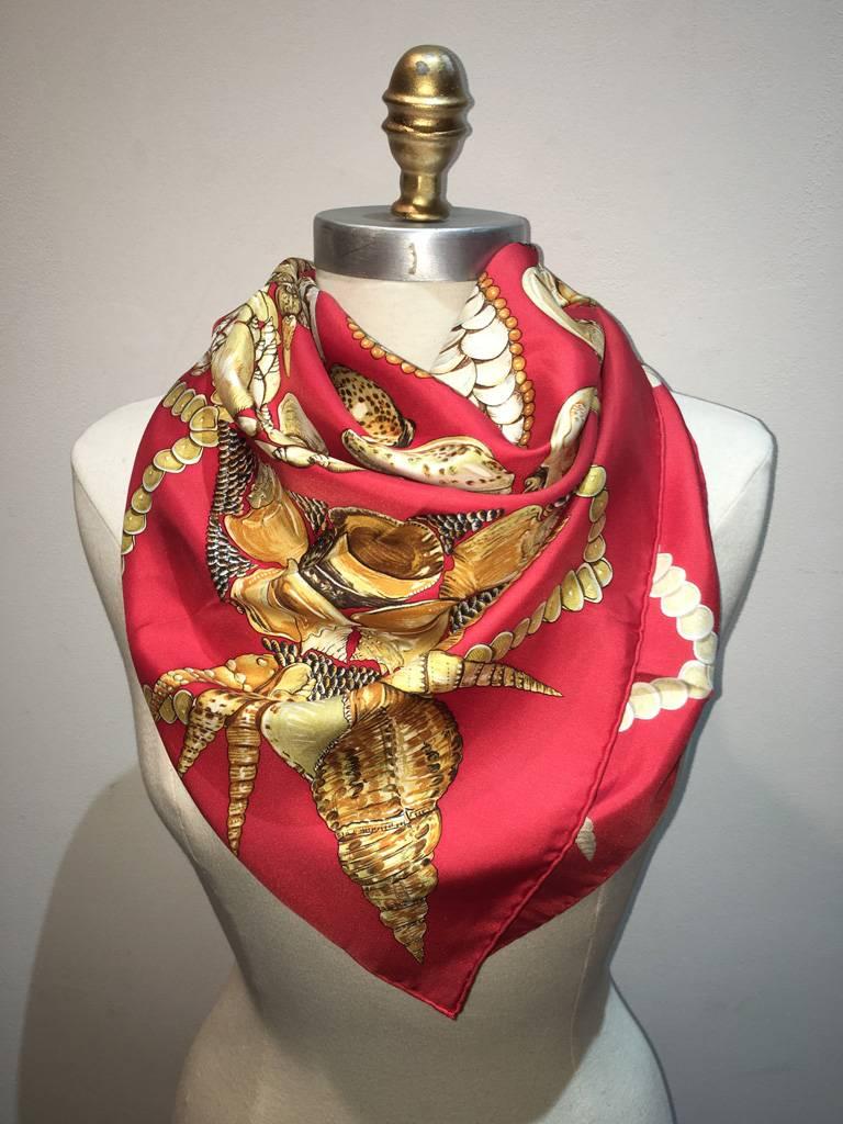 STUNNING Hermes silk Rocaille scarf in red in excellent condition.  Original silk screen design c1999 by Valerie Dawlat-Dumoulin features an array of sea shells making a geometrical pattern over a red background.  100% silk, hand rolled hem, made in