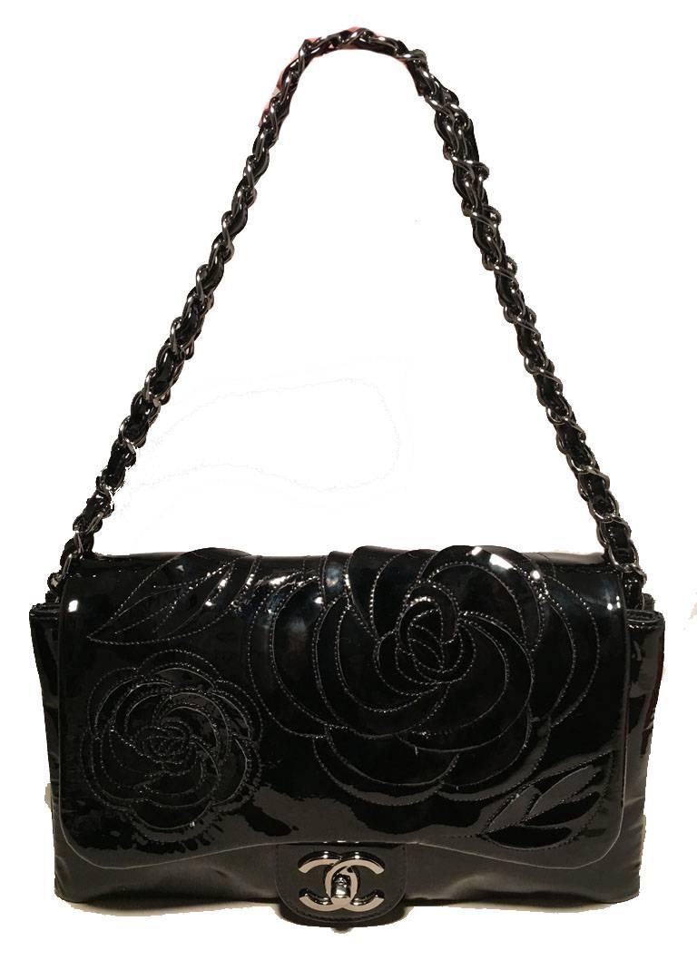Gorgeous Chanel black patent camellia flower classic flap shoulder bag in excellent condition. Black patent leather exterior with camellia flower design cut out along the top front flap. Silver hardware and woven chain and leather shoulder strap. 