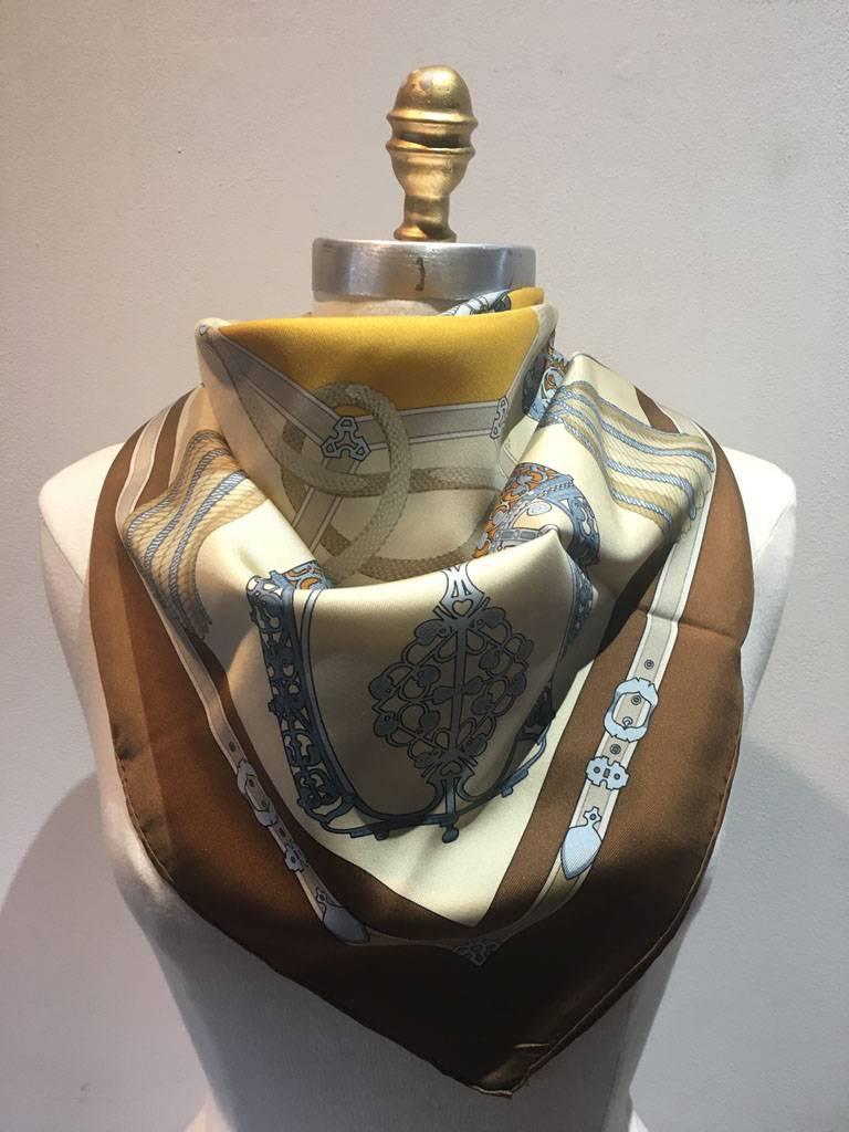 Gorgeous vintage Hermes les Muserolles silk scarf in excellent condition.  Original silk screen design c1986 by Christiane Vauzelles features whimsical silver bridal dressings for any royal knight over a beige background surrounded by a brown
