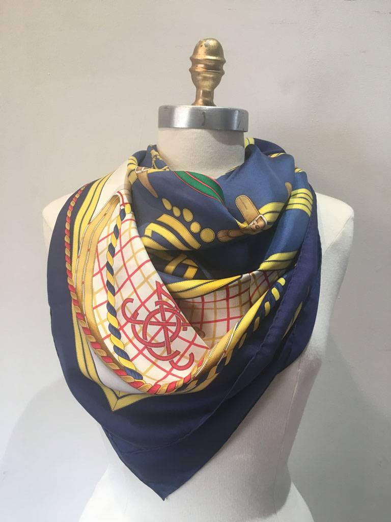 BEAUTIFUL Vintage Hermes Grand Tenues silk scarf in excellent condition.  Original silk screen design c1985 by Henri d'Origny features a traditional ribbon and crown regal design over a golden and white background surrounded by a navy blue border. 