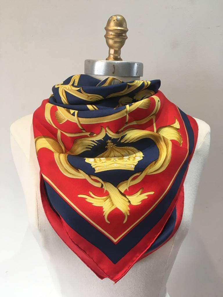 STUNNING Hermes crowns or couronnes silk scarf in excellent vintage condition.  Original silk screen design c1969 by Julia Abadie features an array of golden crowns over a blue background with red border.  This piece is a rare colorway and was made