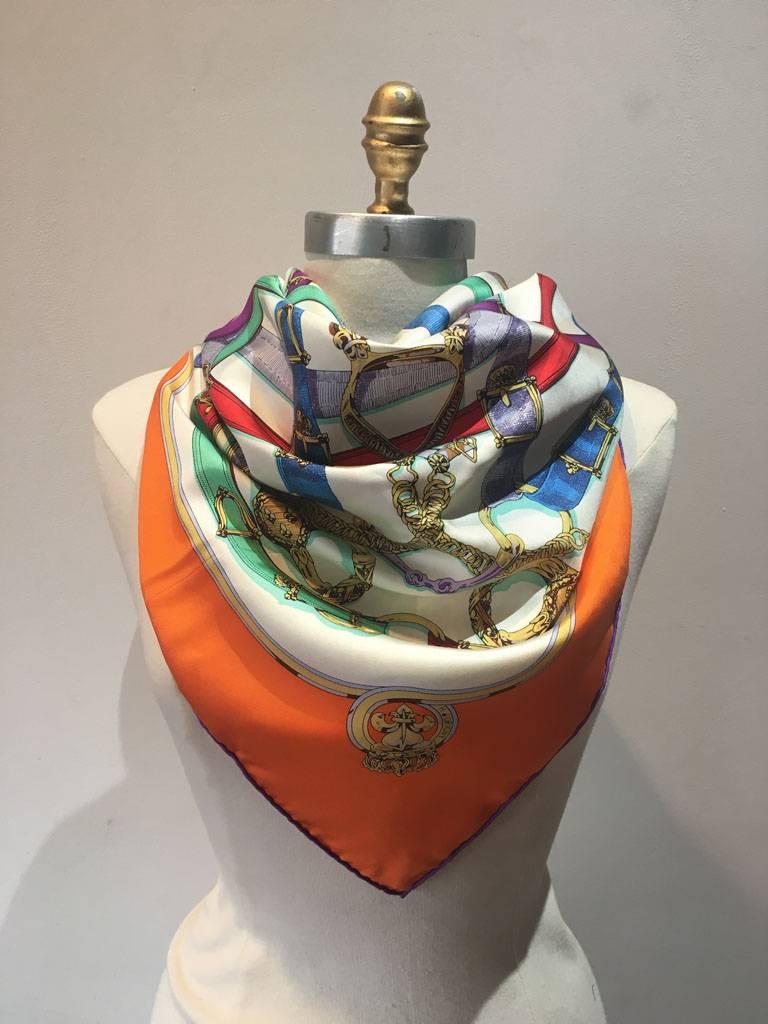 BEAUTIFUL Vintage Hermes silk Cavalcadour scarf in excellent condition.  Original silk screen design c1981 by Henri d'Origny features an assortment of multicolored leather equestrian straps over a cream background surrounded by an orange border. 