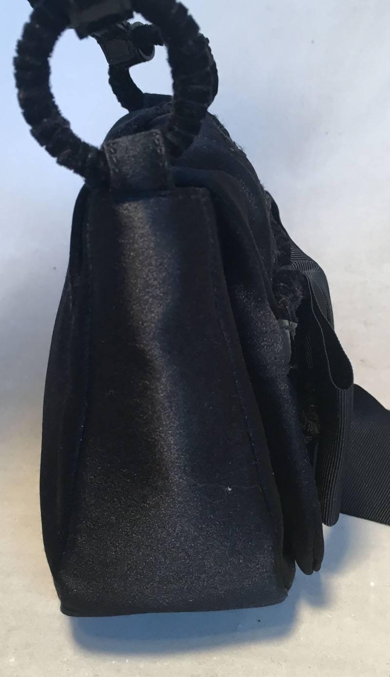 Adorable YSL black silk ribbon evening bag in excellent condition.  Black silk exterior trimmed with a black lace up design along the top front flap, circled velvet covered shoulder strap and a black bow detail along the front side.  Single flap