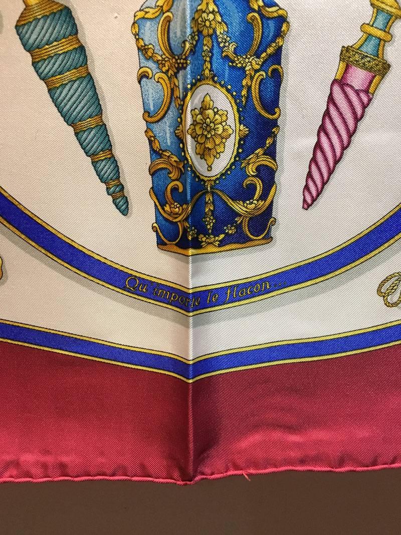AUTHENTIC HERMES silk Qu'Import le Flacon silk scarf in excellent condition. Original silk screen design c1988 by Catherine Baschet features an array of perfume bottles over a cream background surrounded by a dark red border. This piece is in