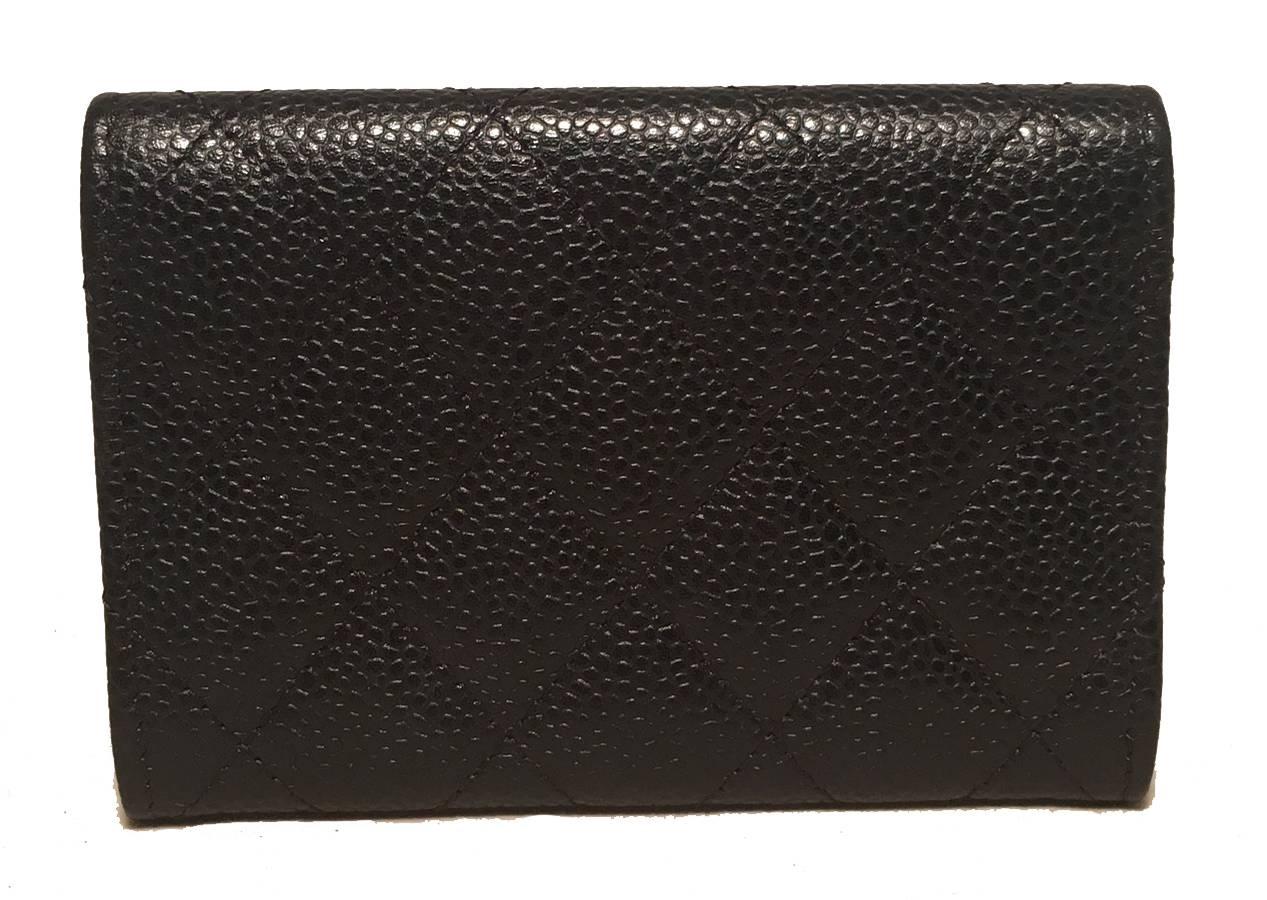 Black quilted caviar leather exterior trimmed with matte gold CC logo along front side. Snap closure opens to a maroon nylon interior that holds one slit card pocket and centered pleated pocket. No stains, smells or scuffs. Perfect petite size for