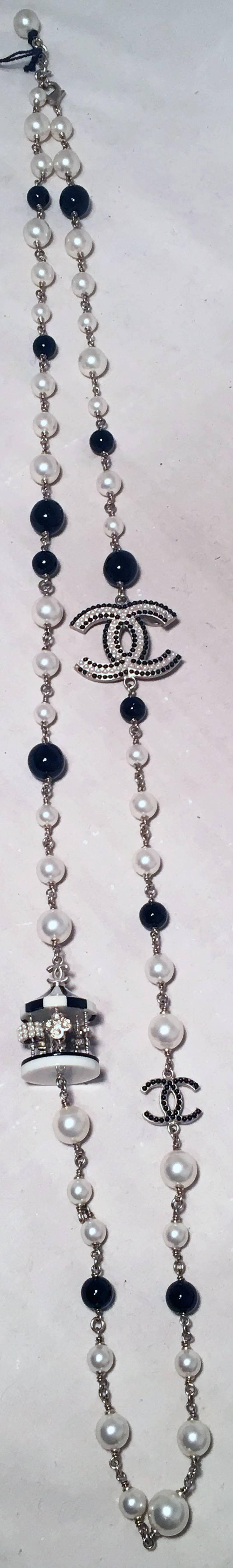 Chanel Black and White Pearl Beaded Carousel Long Necklace in excellent condition.  Black and white varying sized pearls on a silver chain necklace with multiple embellished charms.  2 CC logo charms. smaller one features black beading while the