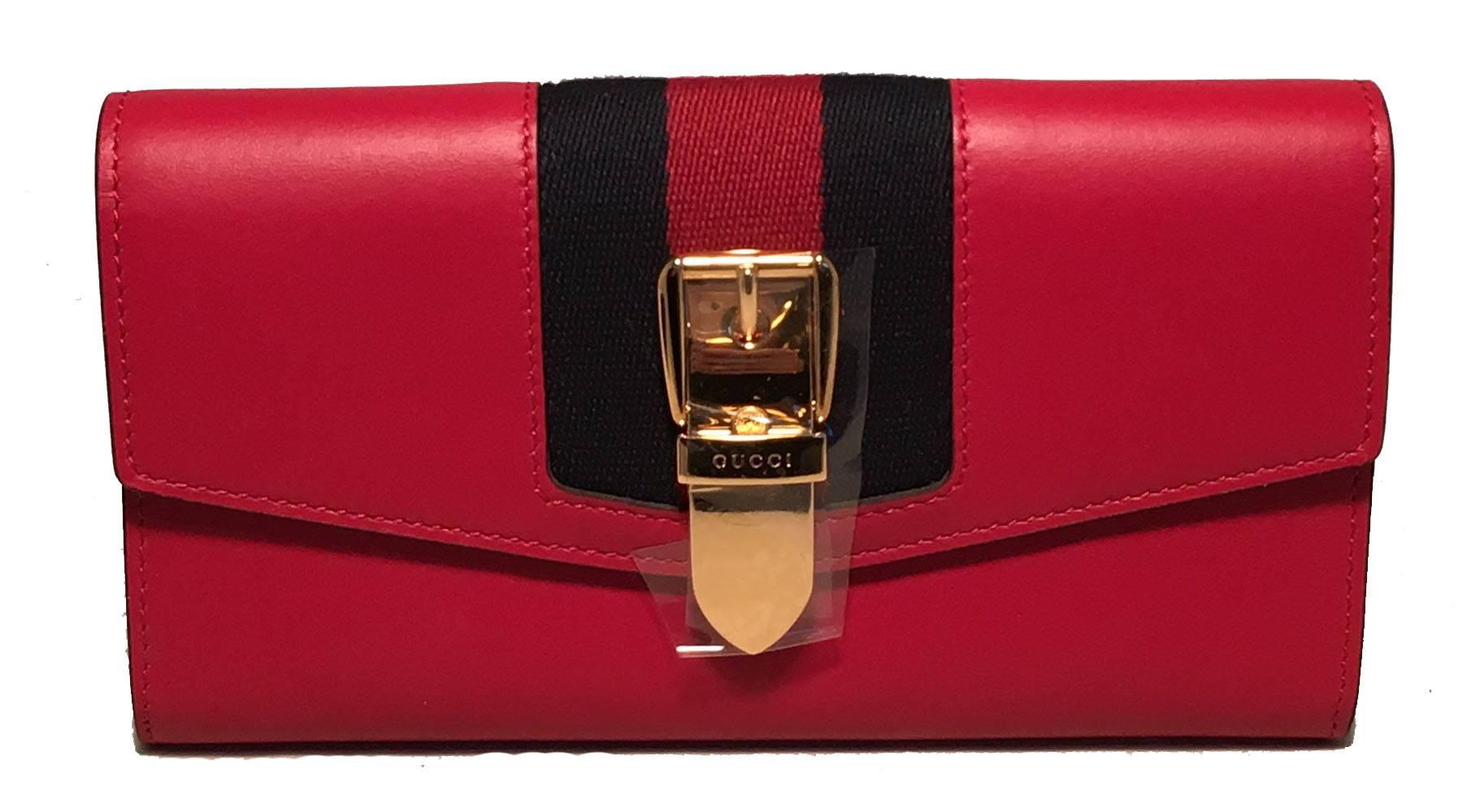 TIMELESS Gucci long sylvie wallet in excellent condition. Red leather exterior trimmed with signature red and black gucci canvas stripes along front with a gold buckle detail along top front flap. Snap flap closure opens to a red leather interior