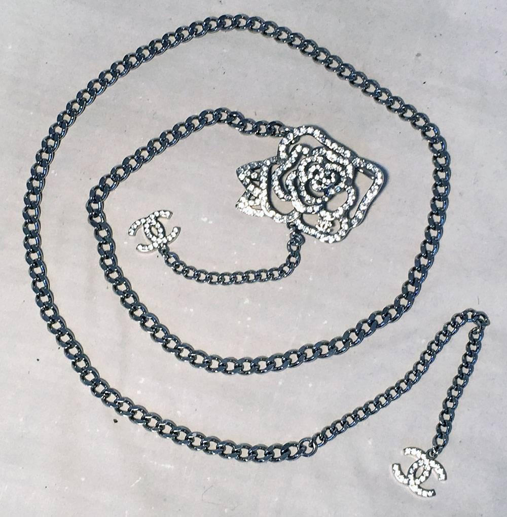GORGEOUS Chanel Silver Chain Rhinestone Camellia Flower Belt Necklace in excellent condition. Silver link chain with rhinestone embellished Camellia flower detail and CC logo rhinestone charms at both ends of chain. Can be worn as a belt or necklace