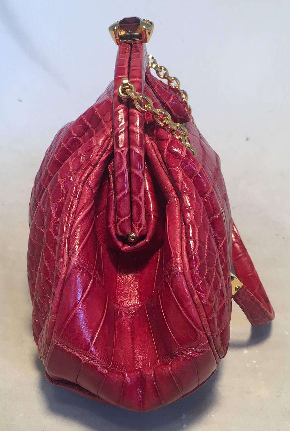 BEAUTIFUL Judith Leiber Small Red Alligator Handbag in excellent condition. Red alligator leather exterior trimmed with gold hardware and a top glass gemstone closure. Red satin interior with one slit and one zipped side pockets. Matching silk mini