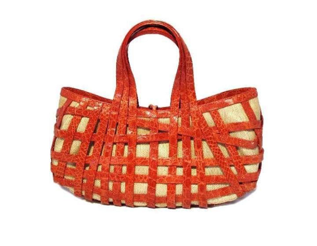 This wonderful Nancy Gonzalez handbag is in excellent condition. The exterior features an intricate basket pattern of red crocodile leather surrounding a beige underlining. The simple loop closure opens to a fully lined beige suede interior that