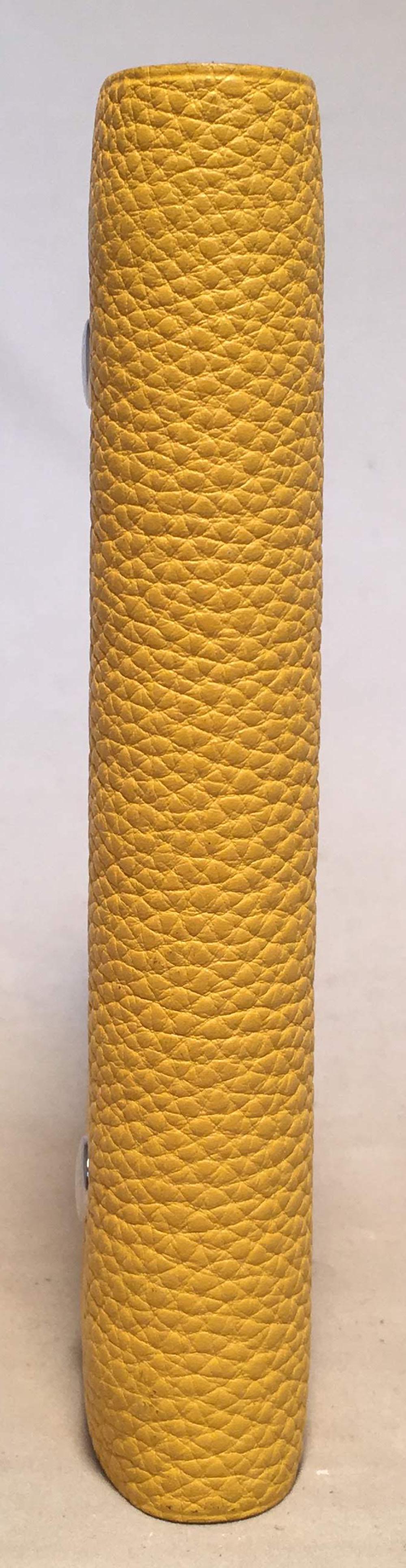Adorable Hermes Yellow Clemence Leather Notebook in excellent condition. Yellow clemence leather exterior trimmed with silver palladium snaps. Snap closure opens to an unused spiral bound paper notebook that can easily be replaced when needed.