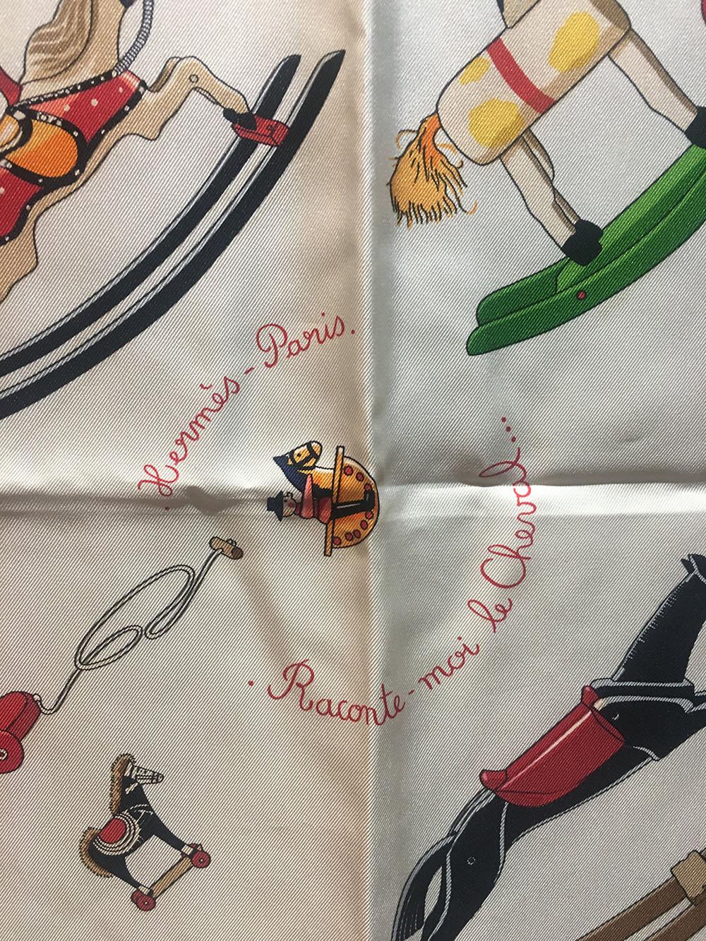 RARE Limited Edition Hermes Raconte-Moi Le Cheval Silk Scarf in Red in excellent condition. Original silk screen design c2000 by Dimitri Rybaltchenko features various multi color rocking horses over an ivory background surrounded by a thin red